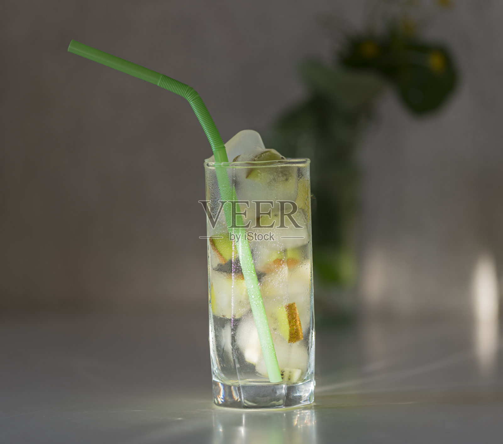 自制的冰鲜柠檬水加冰块，在白色的桌子上，在雾气蒙蒙的玻璃杯里点缀着新鲜的酸橙片和水滴照片摄影图片