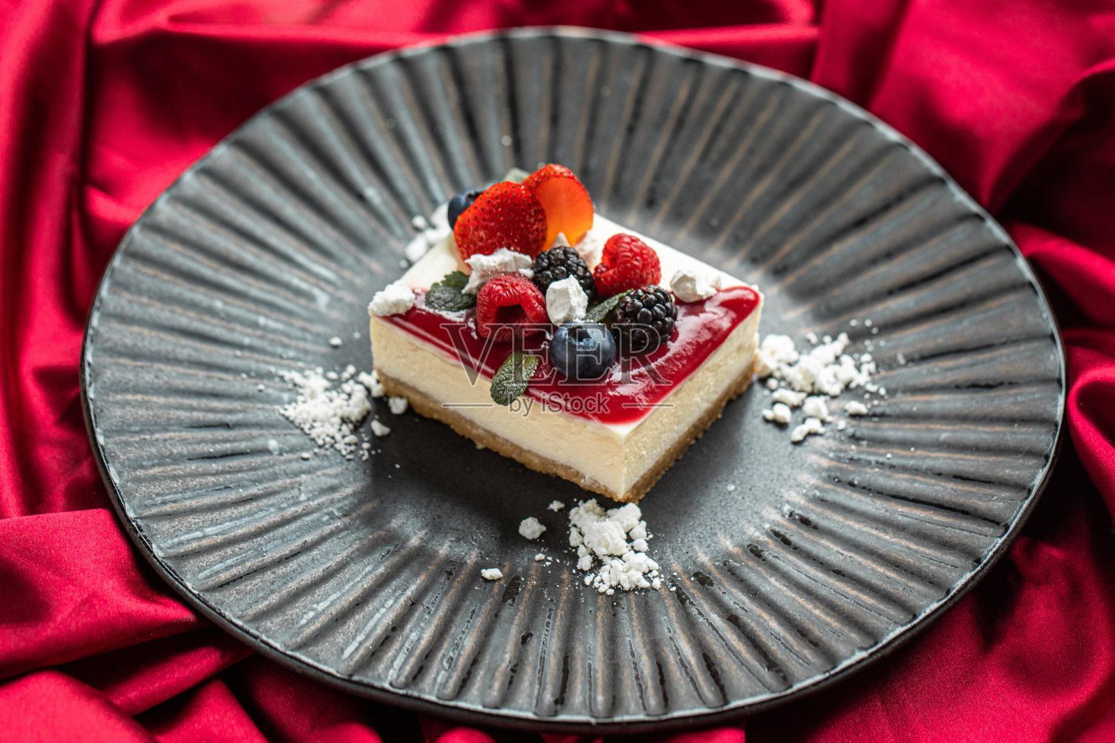 黑色碗和奶酪蛋糕，草莓奶酪蛋糕在黑色陶瓷盘。照片摄影图片