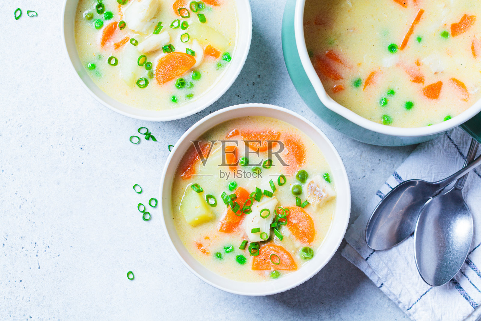 白碗里的鳕鱼浓汤配青豌豆、土豆和胡萝卜。照片摄影图片