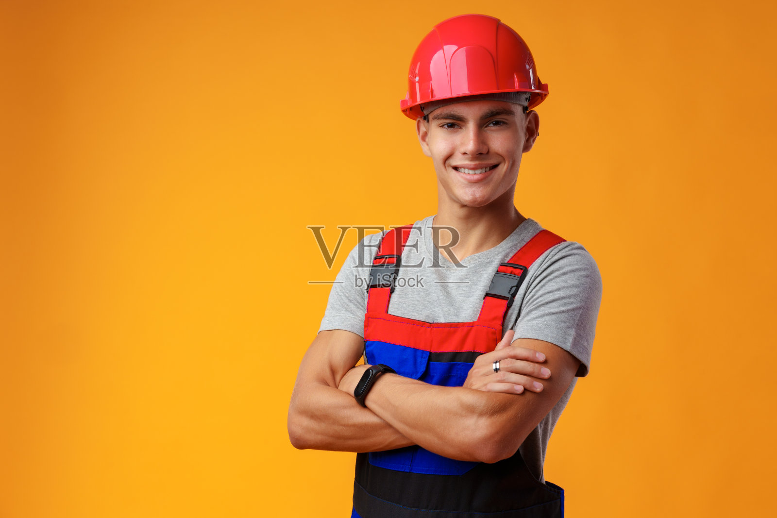 年轻的建筑工人戴着头盔和制服在工作室的黄色背景上摆姿势照片摄影图片