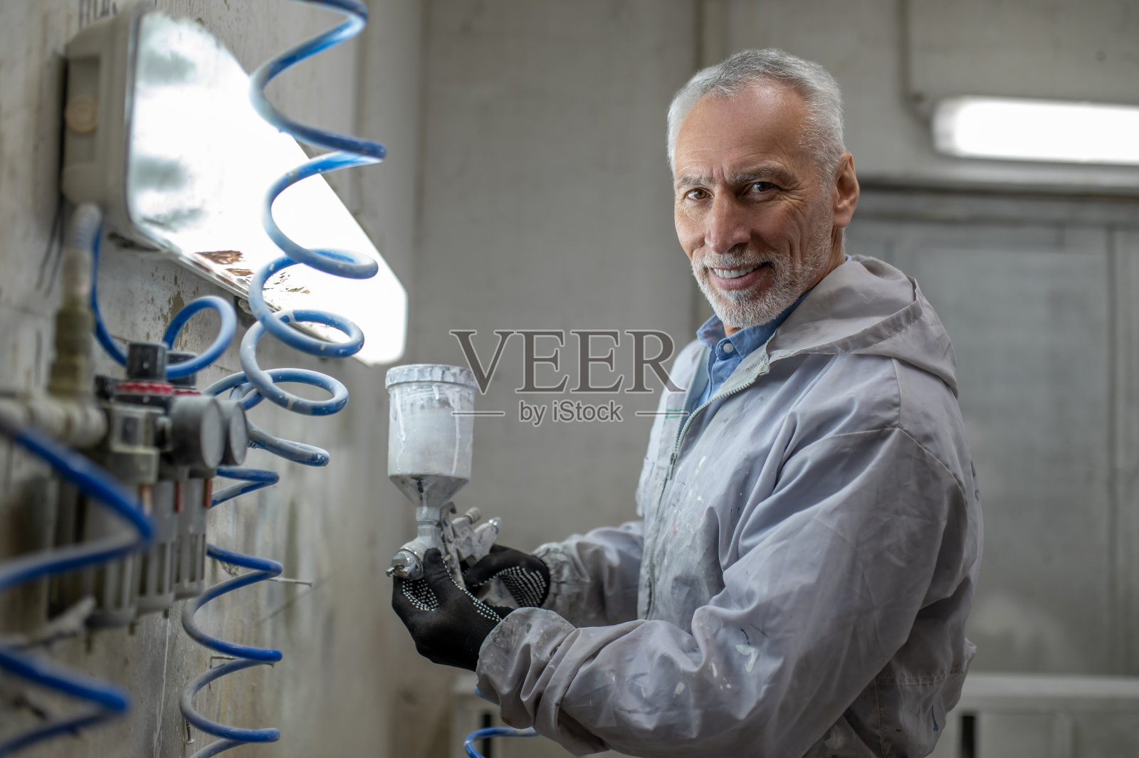 拿着喷枪的男人站在画室里照片摄影图片