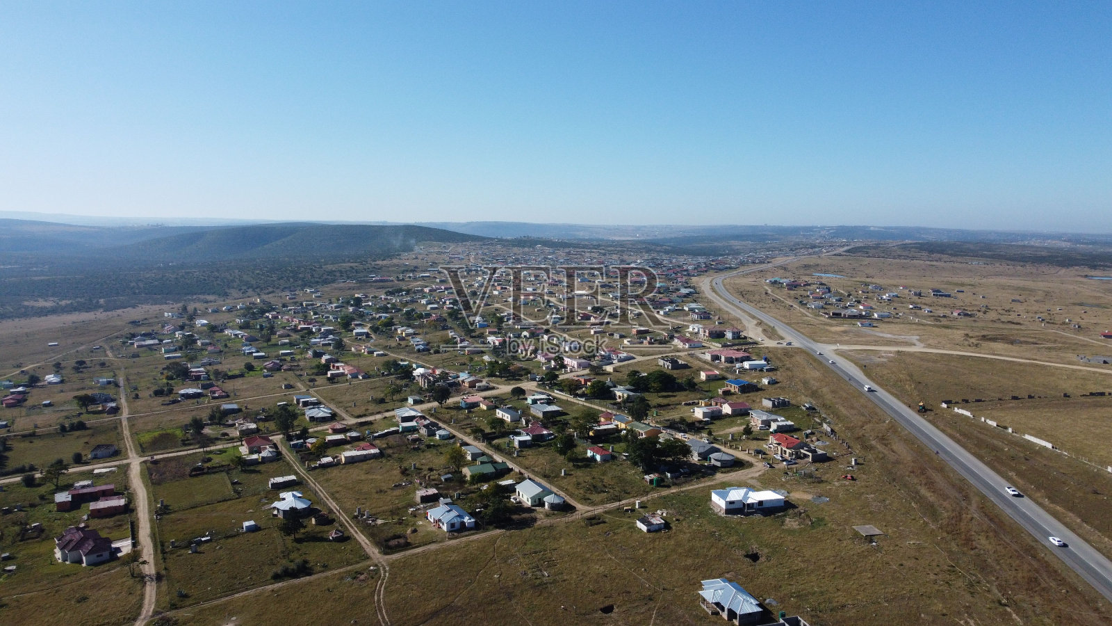 阳光明媚的一天，绿色农田附近的乡村房屋鸟瞰图照片摄影图片
