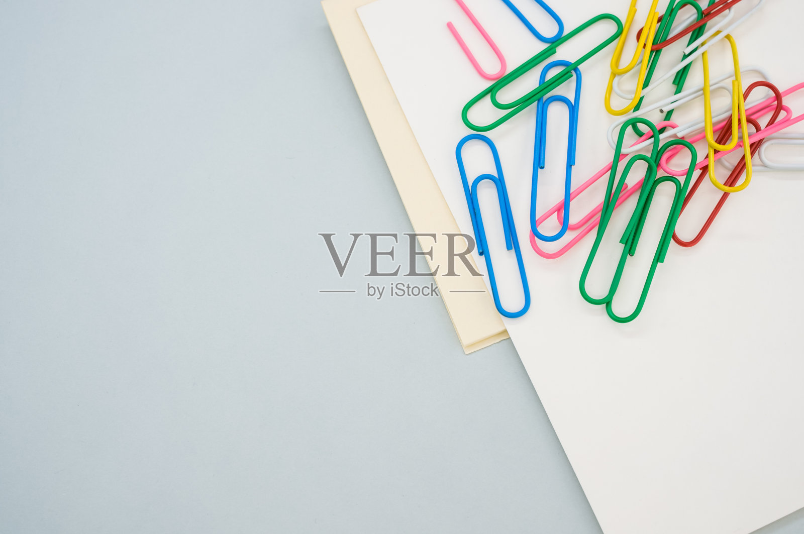 特写镜头的空白纸与彩色回形针在浅绿色的背景照片摄影图片