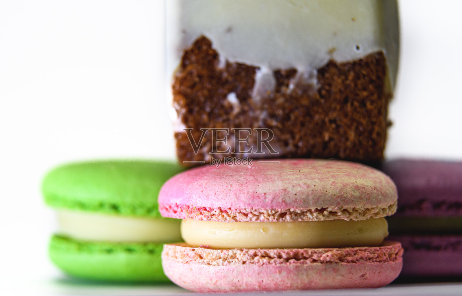 美味的彩色法式马卡龙，白色的背景上有一块蛋糕照片摄影图片