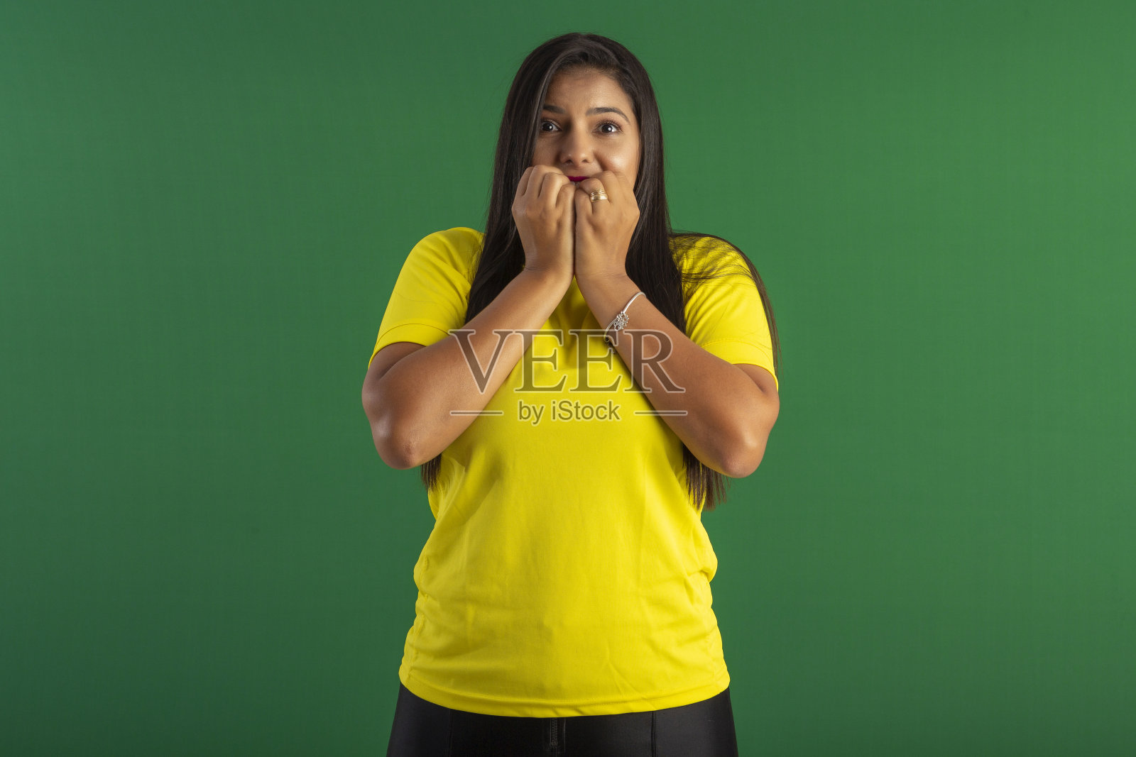 年轻女子在圣诞老人的服装和帽子，在工作室照片与蓝色背景和圣诞主题照片摄影图片