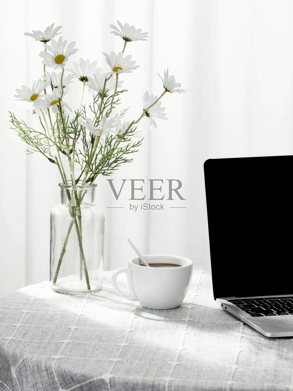 垂直拍摄一台笔记本电脑和一杯咖啡，旁边是一个装满鲜花的花瓶，在室内照片摄影图片