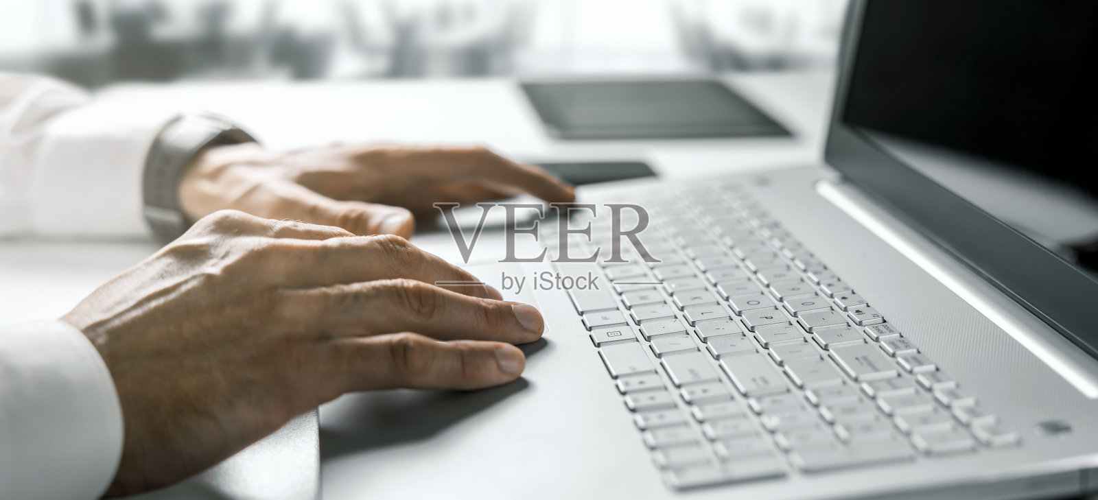 商务人士在明亮的现代办公室里用手提电脑打字。带有复制空间的横幅照片摄影图片