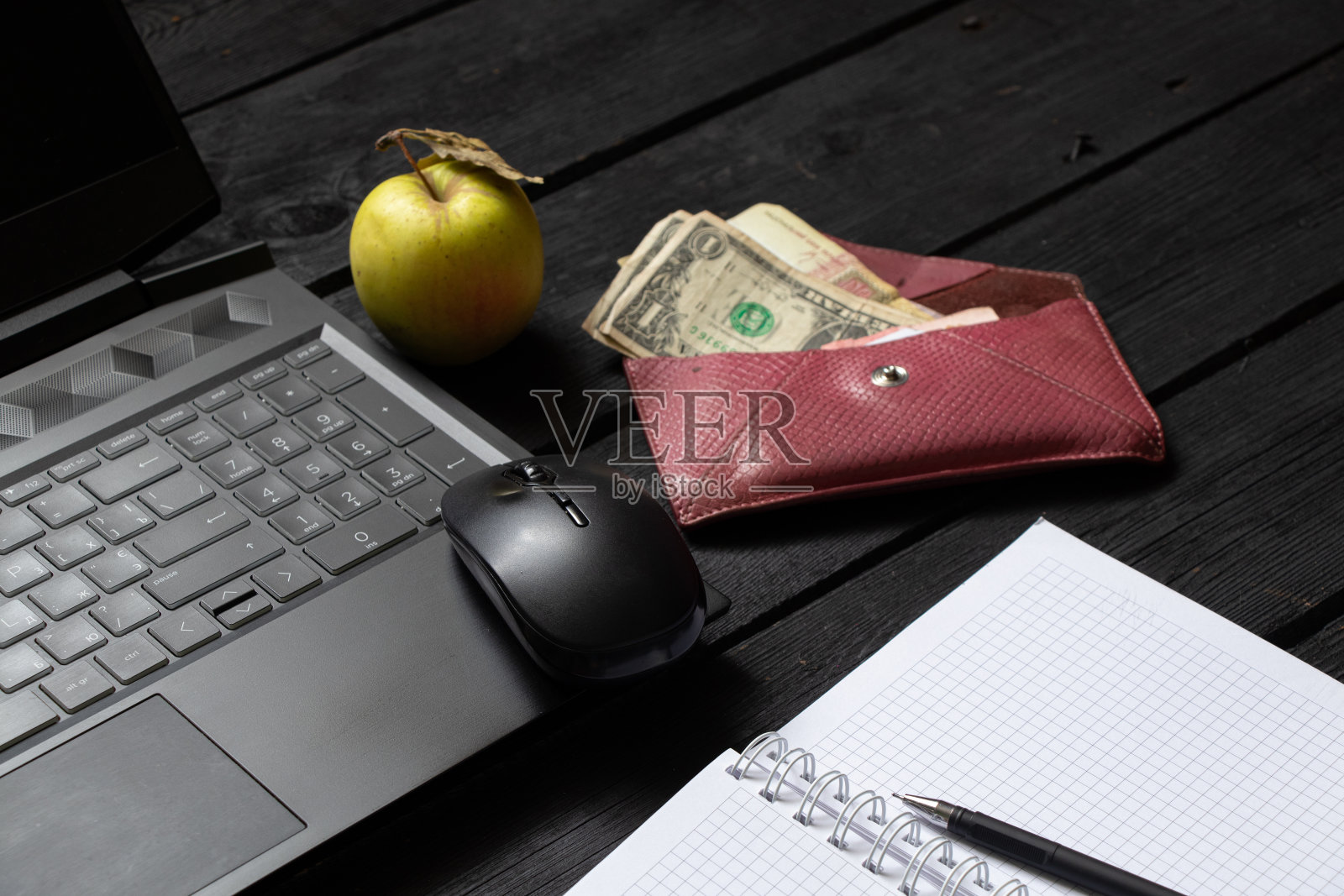 笔记本笔记本苹果钱躺在工作的黑色木桌上，笔记本电脑在工作时放在工作桌上，创作过程中，自由职业者的工作场所照片摄影图片