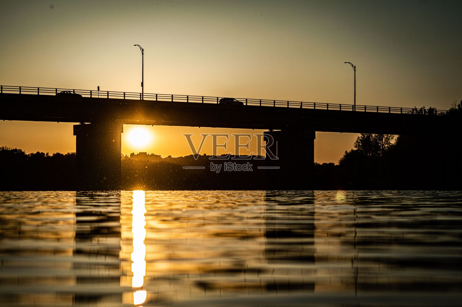 夕阳下，一座桥的剪影，上面有汽车，下面有一条河照片摄影图片