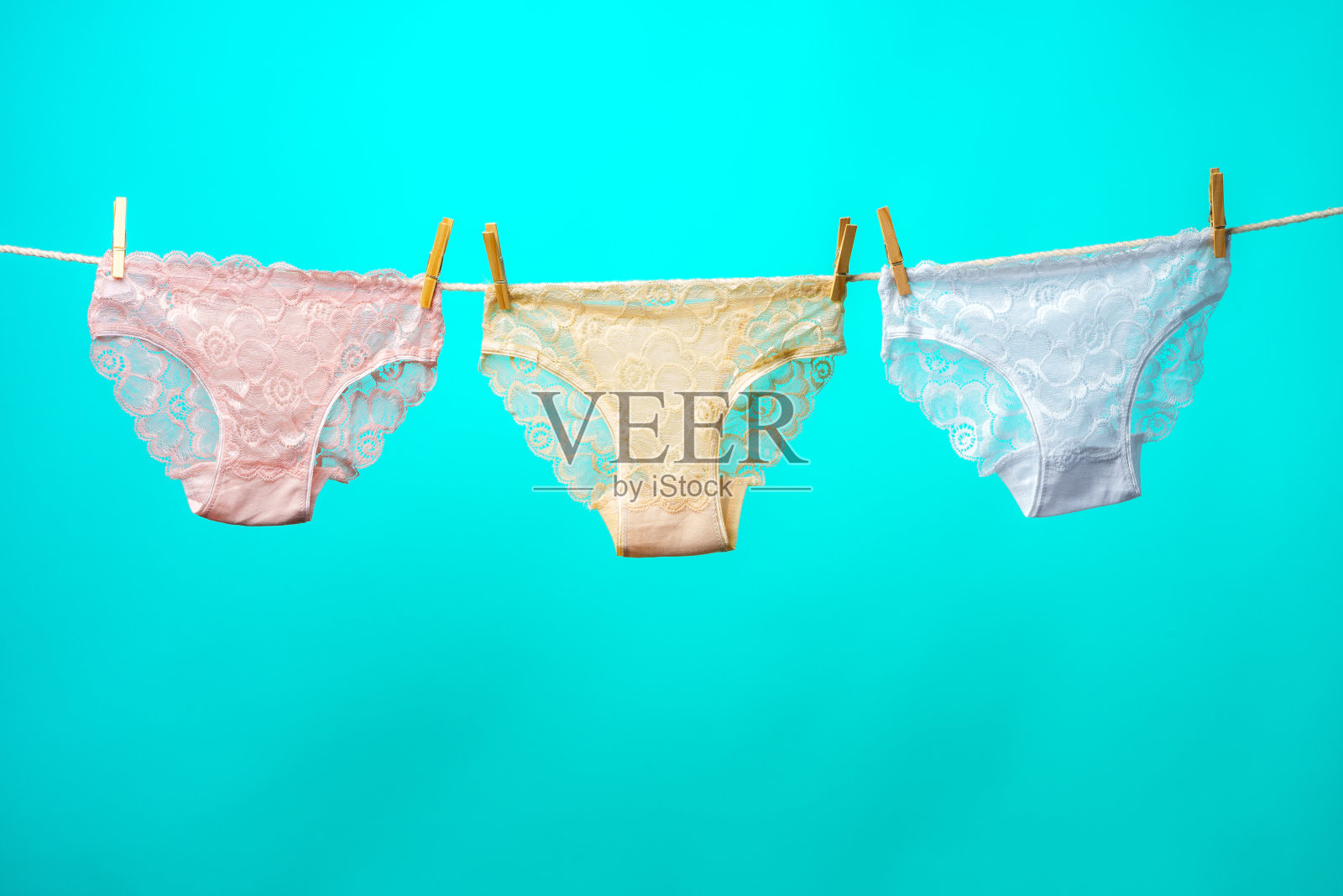 女性内裤挂在绳子上对蓝色的工作室背景照片摄影图片