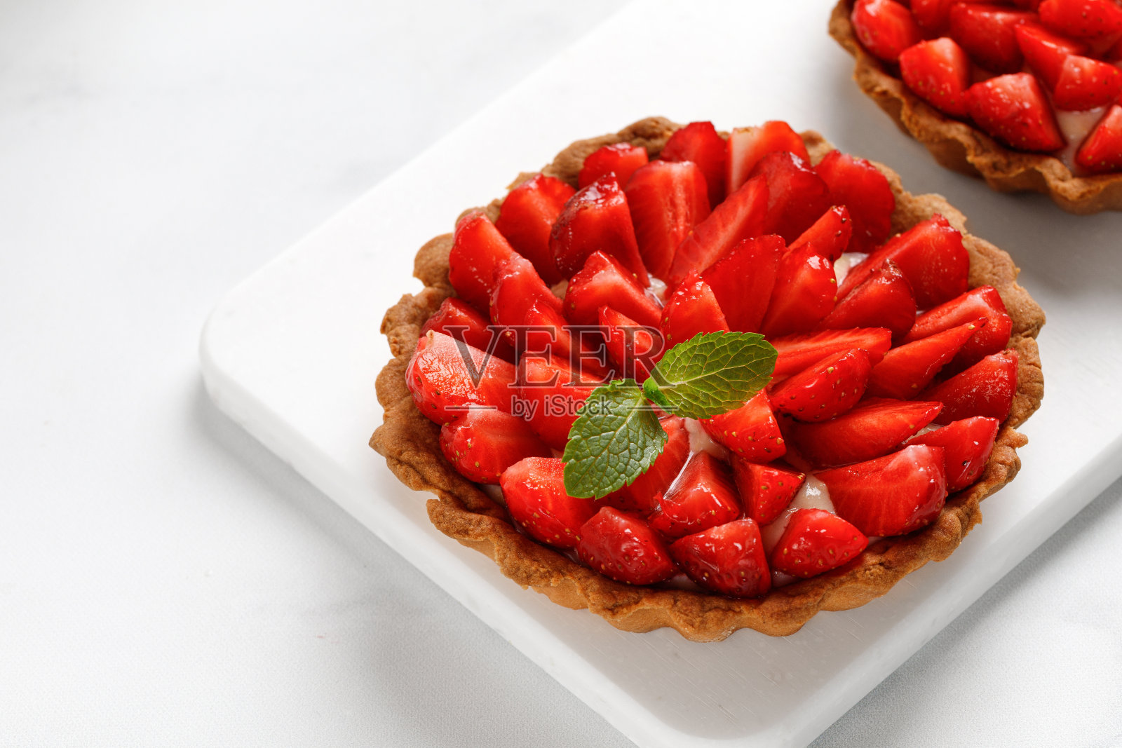 用草莓和香草奶油在白板和白色背景上的蛋挞，特写。本空间照片摄影图片