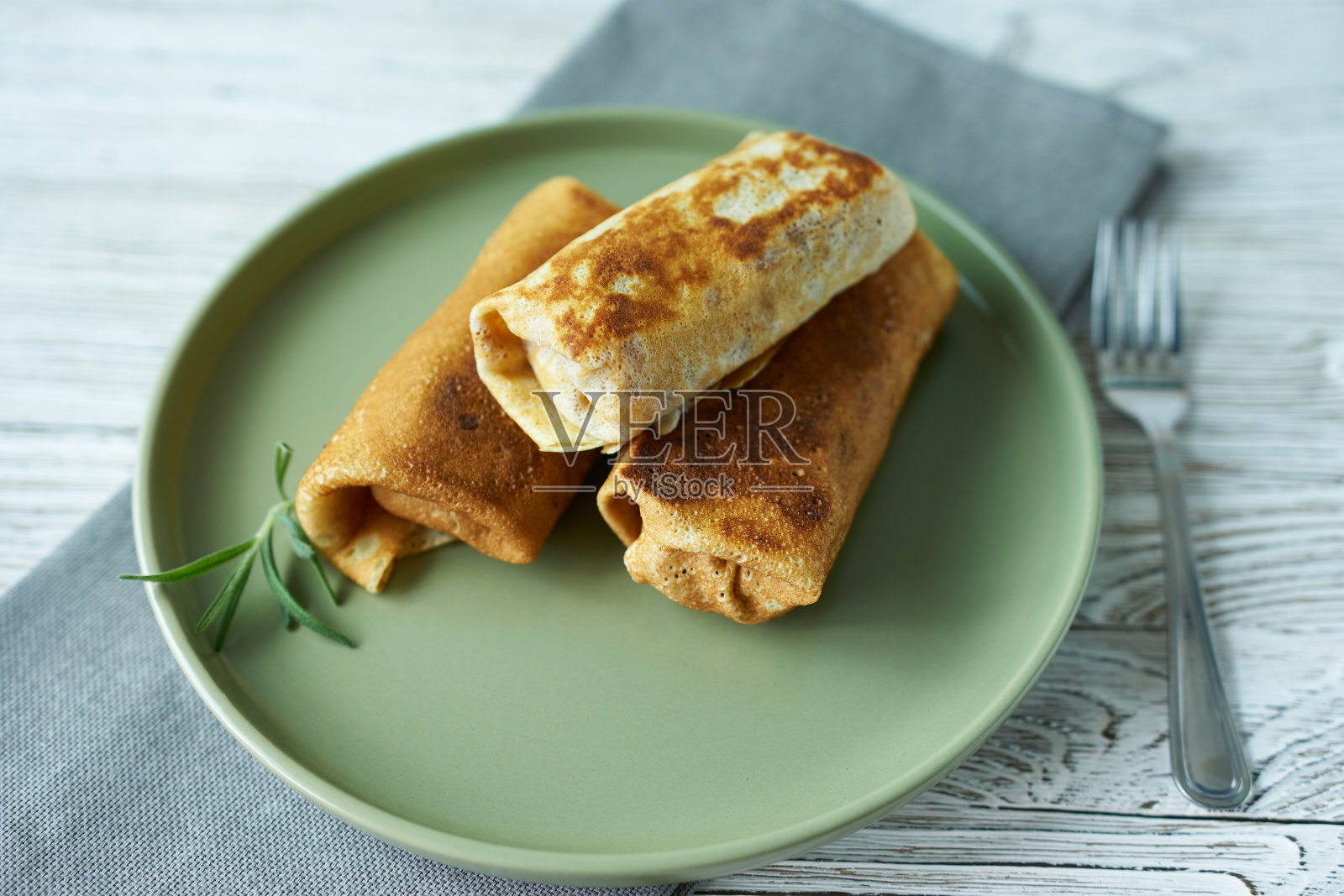 煎饼卷放在绿色的盘子上，配上迷迭香，特写。照片摄影图片