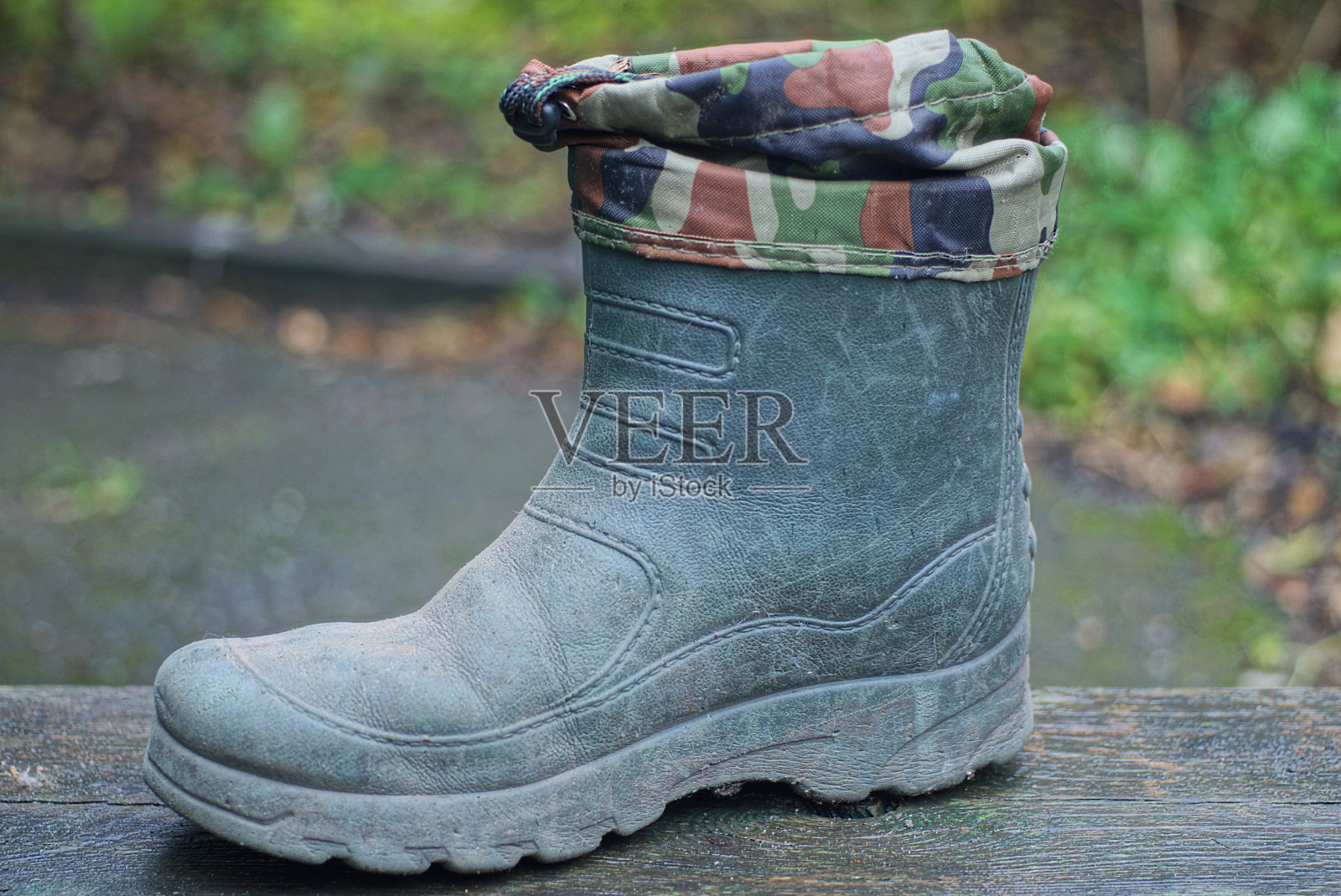 一只由橡胶和斑点织物制成的绿色大靴子照片摄影图片