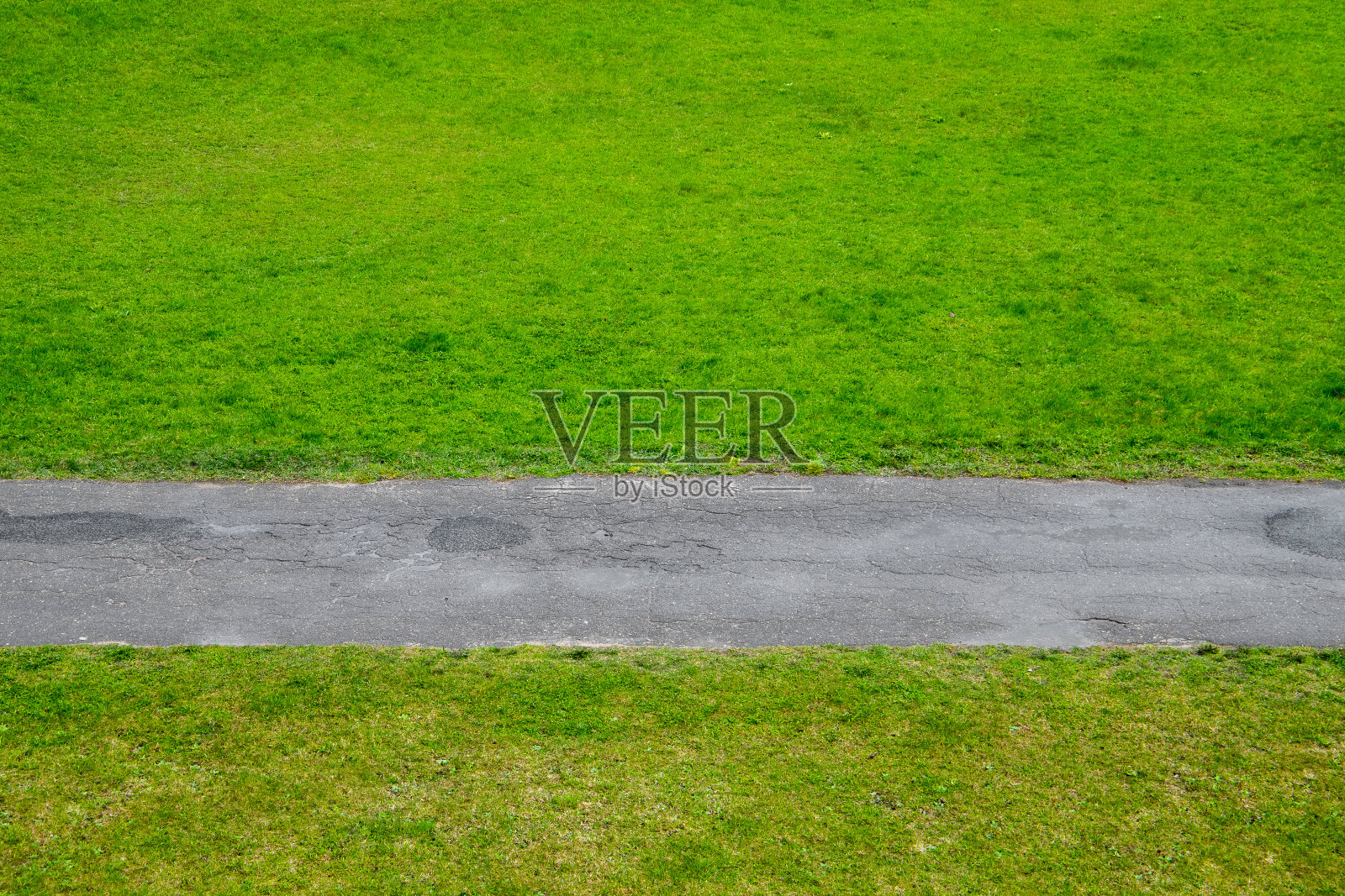 柏油路穿过绿色的草坪，抽象的背景照片摄影图片