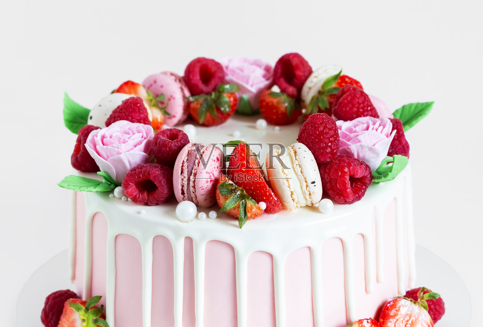 用马卡龙、覆盆子、草莓和糖玫瑰装饰的漂亮的粉色蛋糕。照片摄影图片