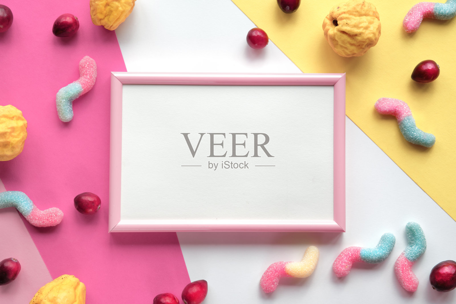 空白的粉白色框架上分层彩色纸。各种各样的糖果，糖果和蔓越莓浆果周围的空框与复制空间，放置文本。平铺，俯视图。照片摄影图片