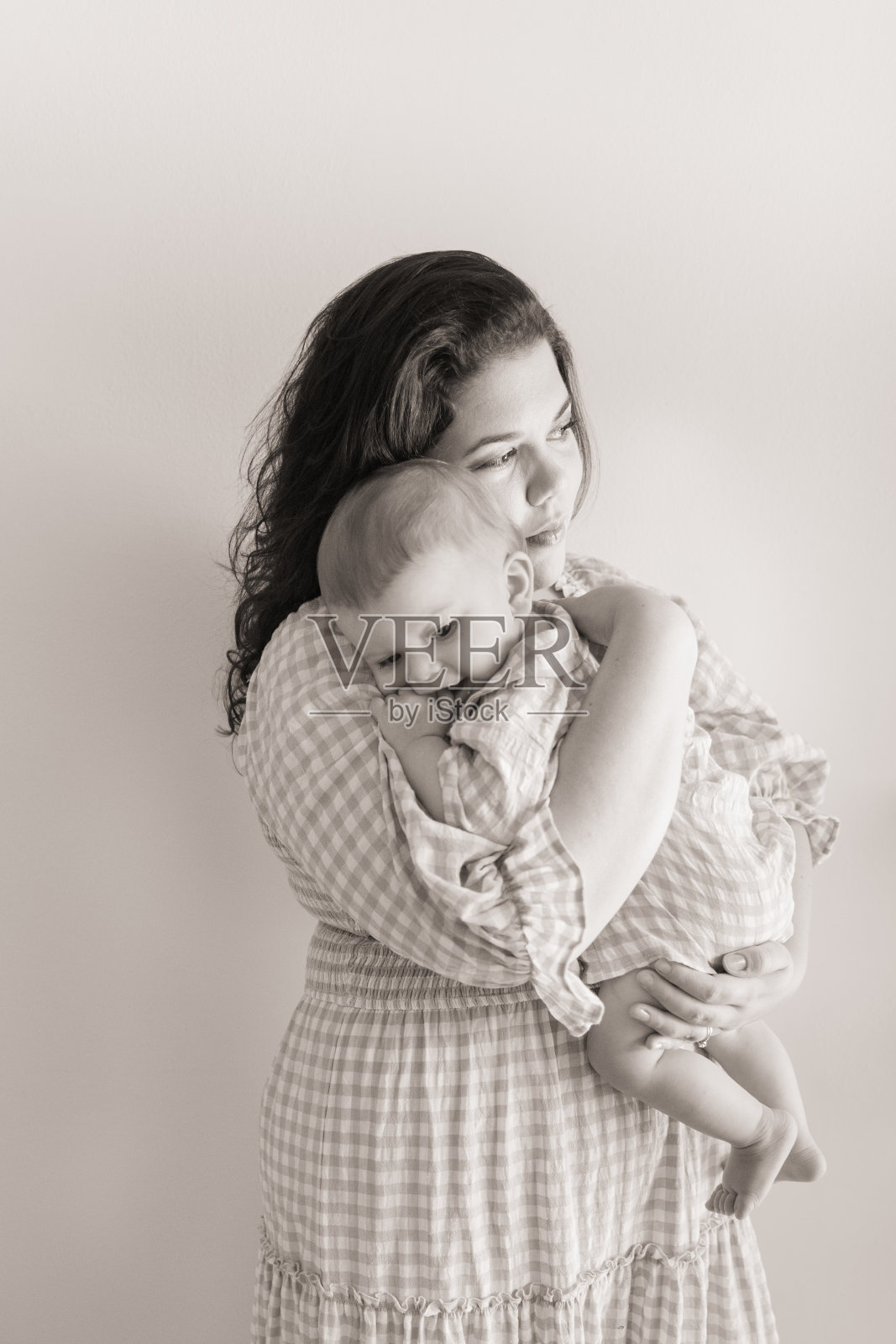 2022年秋天，一个9个月大的男婴被他31岁的母亲抱在怀里，他们穿着相配的格纹套装照片摄影图片