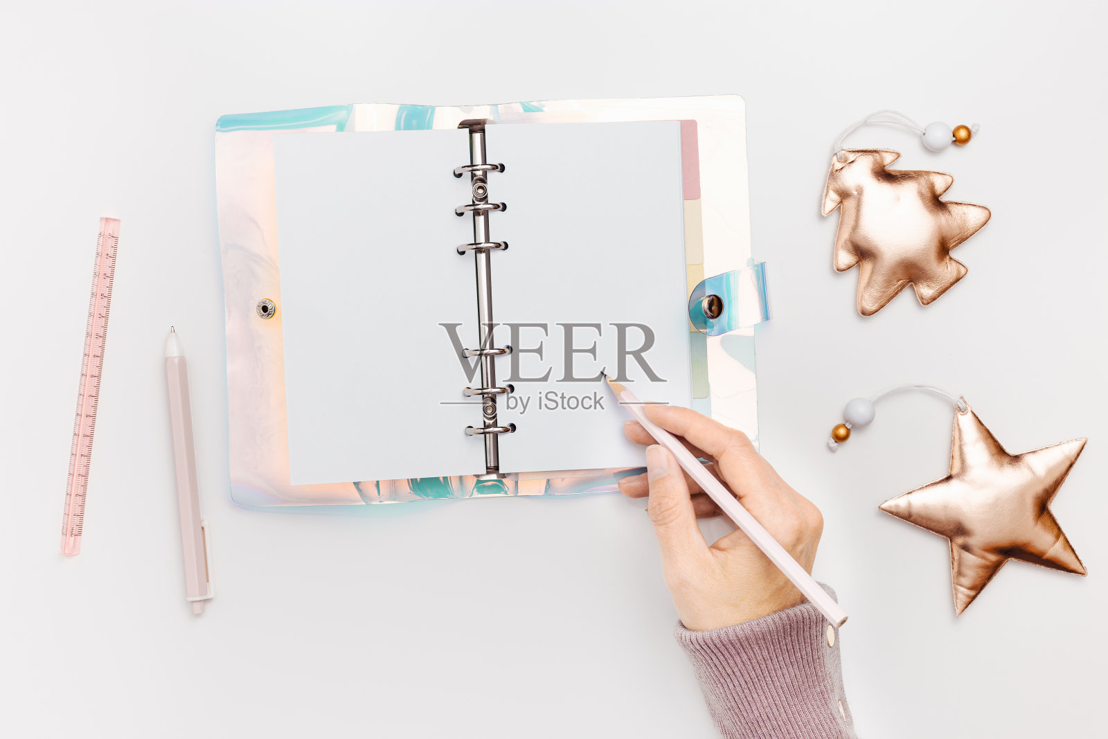新年计划概念，女人拿着铅笔，写在打开空白的抄写本或日记本上。粉色金属色圣诞树和闪亮的星星玩具。学校或家庭办公文具照片摄影图片