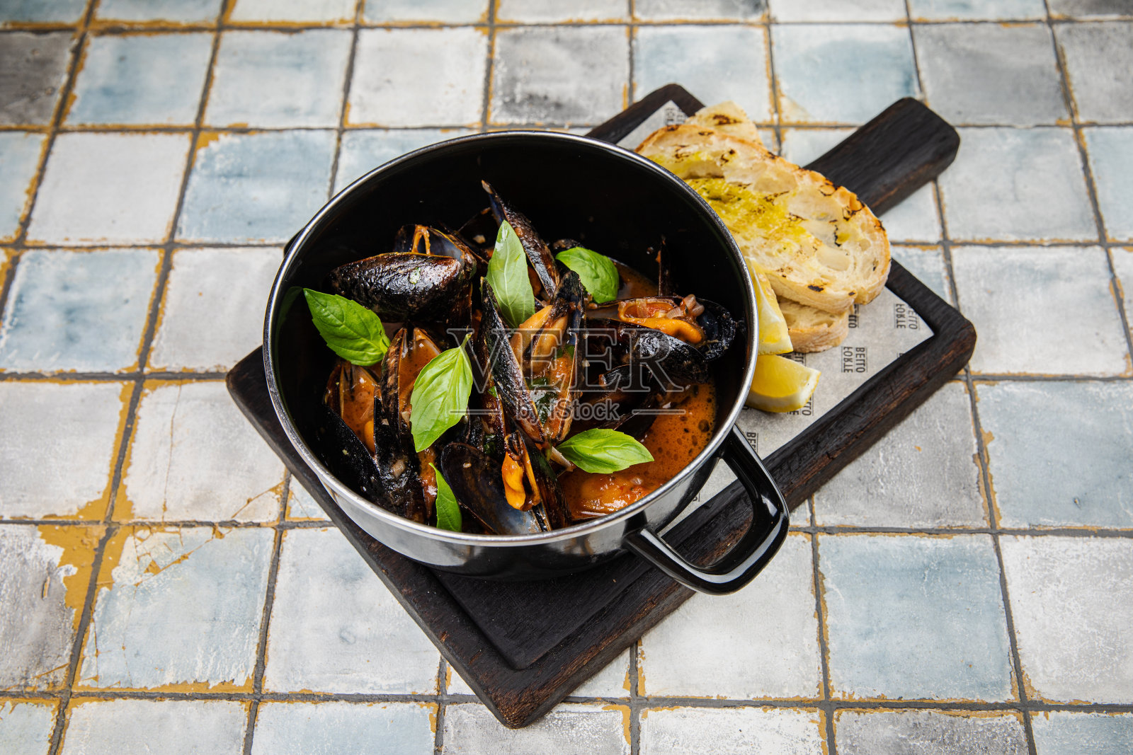 蓝贻贝配新鲜贻贝在锅里，新鲜贻贝配香草在碗里加柠檬照片摄影图片