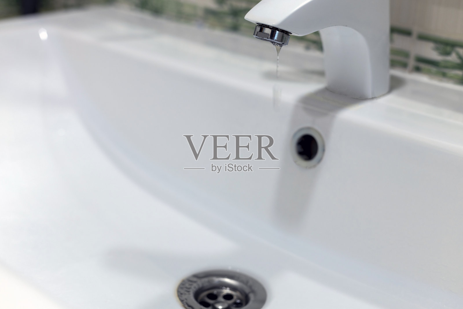 干净的水从水龙头流入白色的洗涤槽。管道照片摄影图片