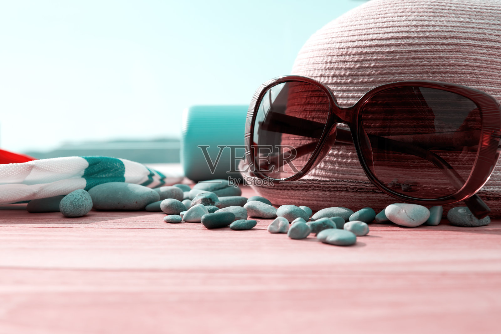 草帽、奶油瓶、太阳镜和露台木桌上的鹅卵石照片摄影图片