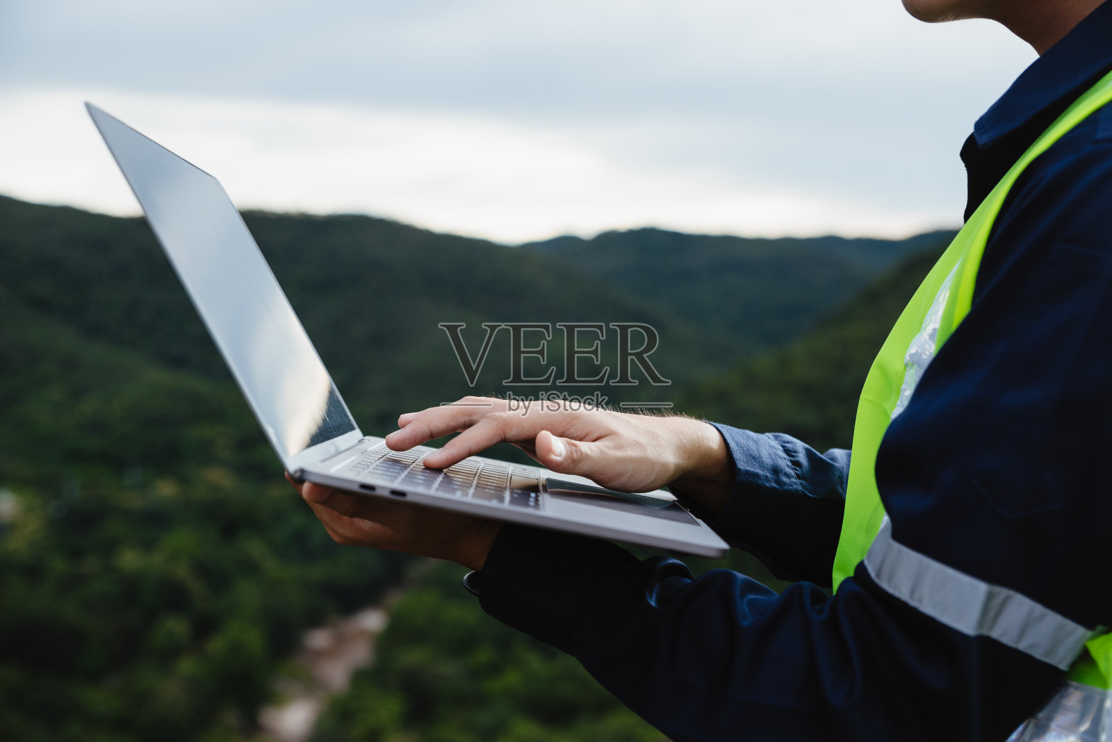 年轻的维修工程师在山上用笔记本电脑工作。照片摄影图片