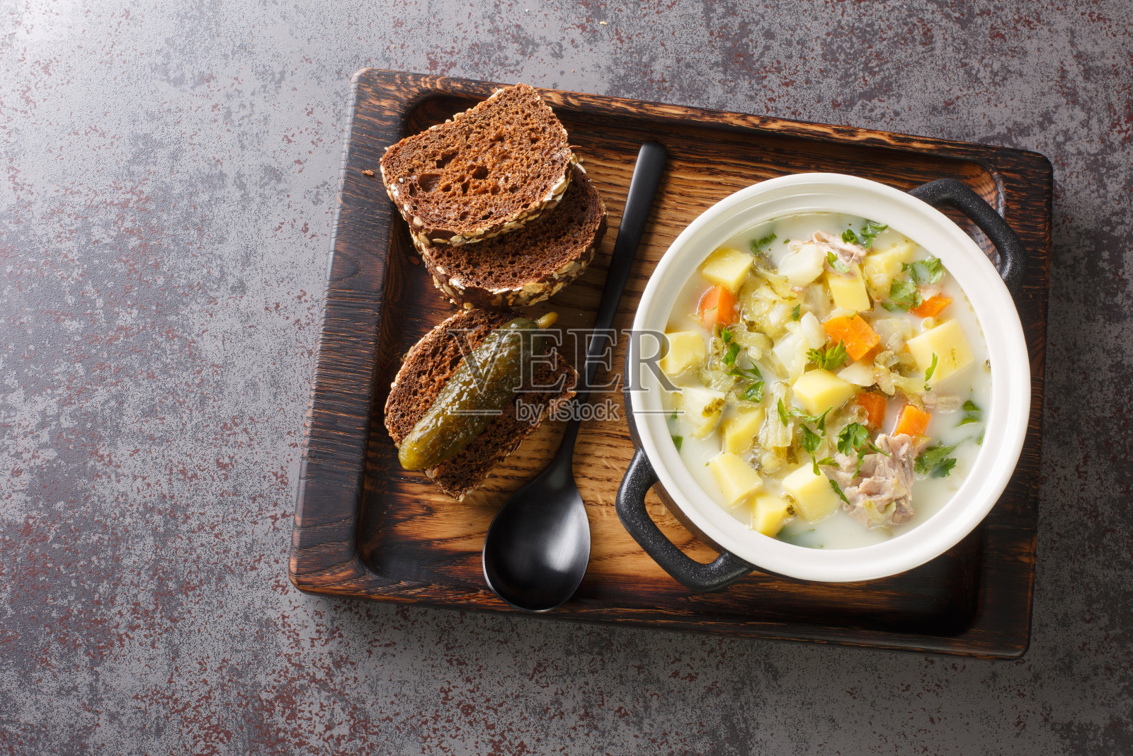 Ogorkowa Zupa奶油波兰莳萝泡菜汤与根蔬菜特写在木托盘上。水平的俯视图照片摄影图片