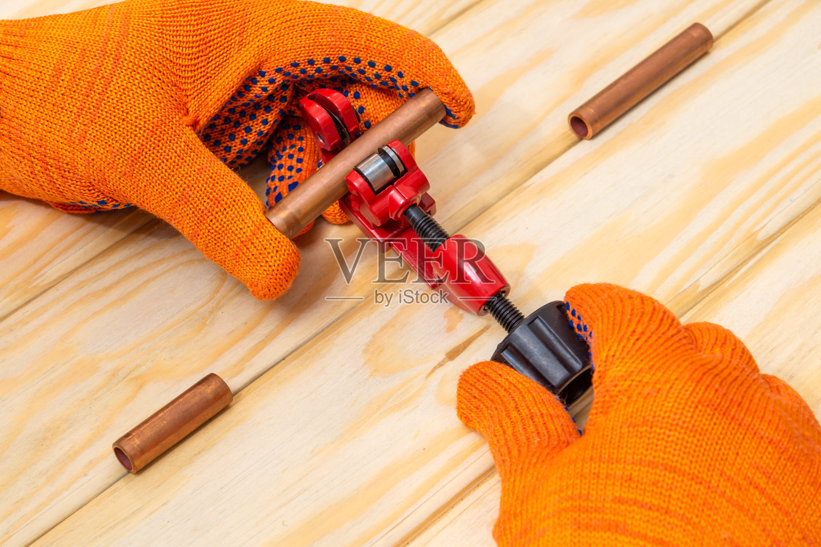 管道工师傅在木桌上用剪管器切割铜管照片摄影图片