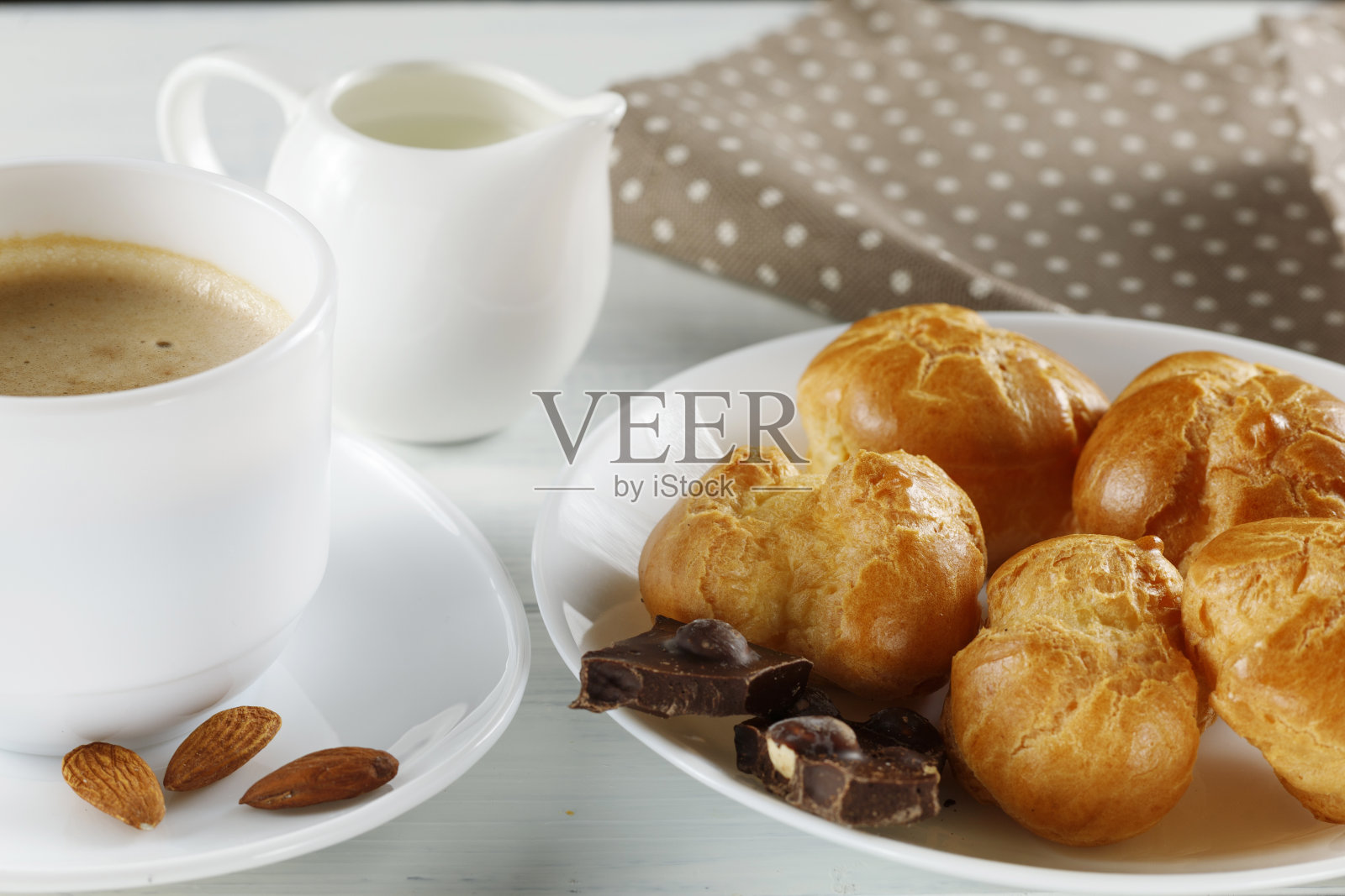 加巧克力、卡布奇诺和牛奶的泡芙。甜蜜的早餐。奶油巧克力泡芙照片摄影图片