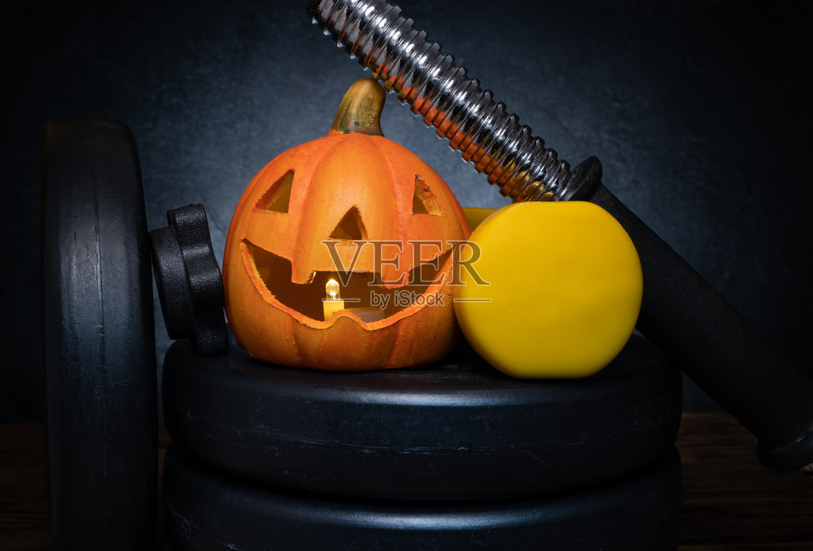 万圣节的陶瓷灯笼南瓜和健身房哑铃哑铃盘子组成。照片摄影图片