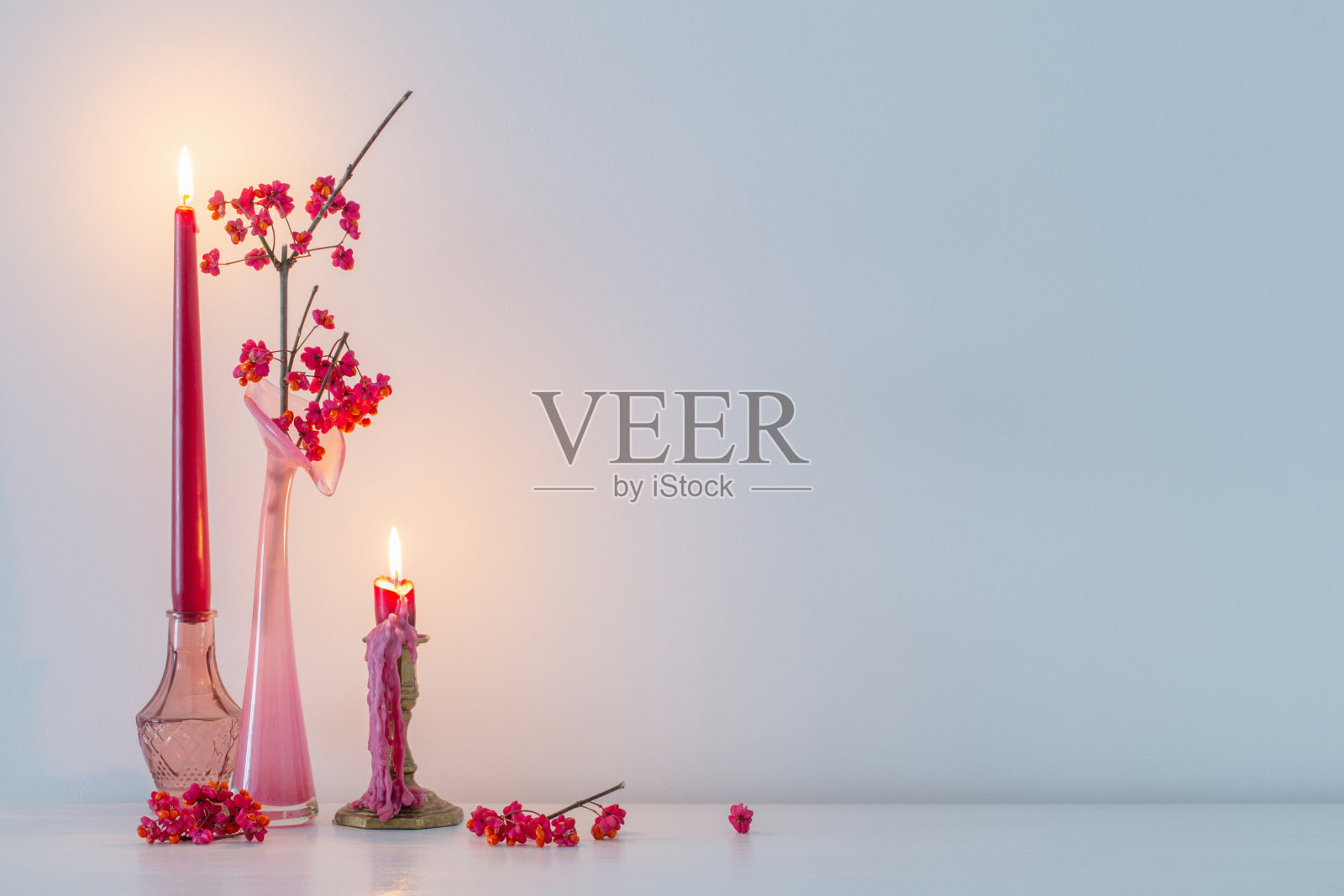 粉红色的圣诞装饰和白色的室内燃烧的蜡烛照片摄影图片