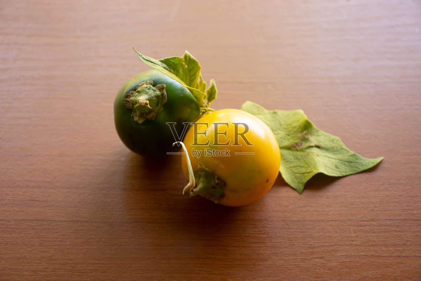 棕色的桌子上放着两株绿黄酸的茄子照片摄影图片