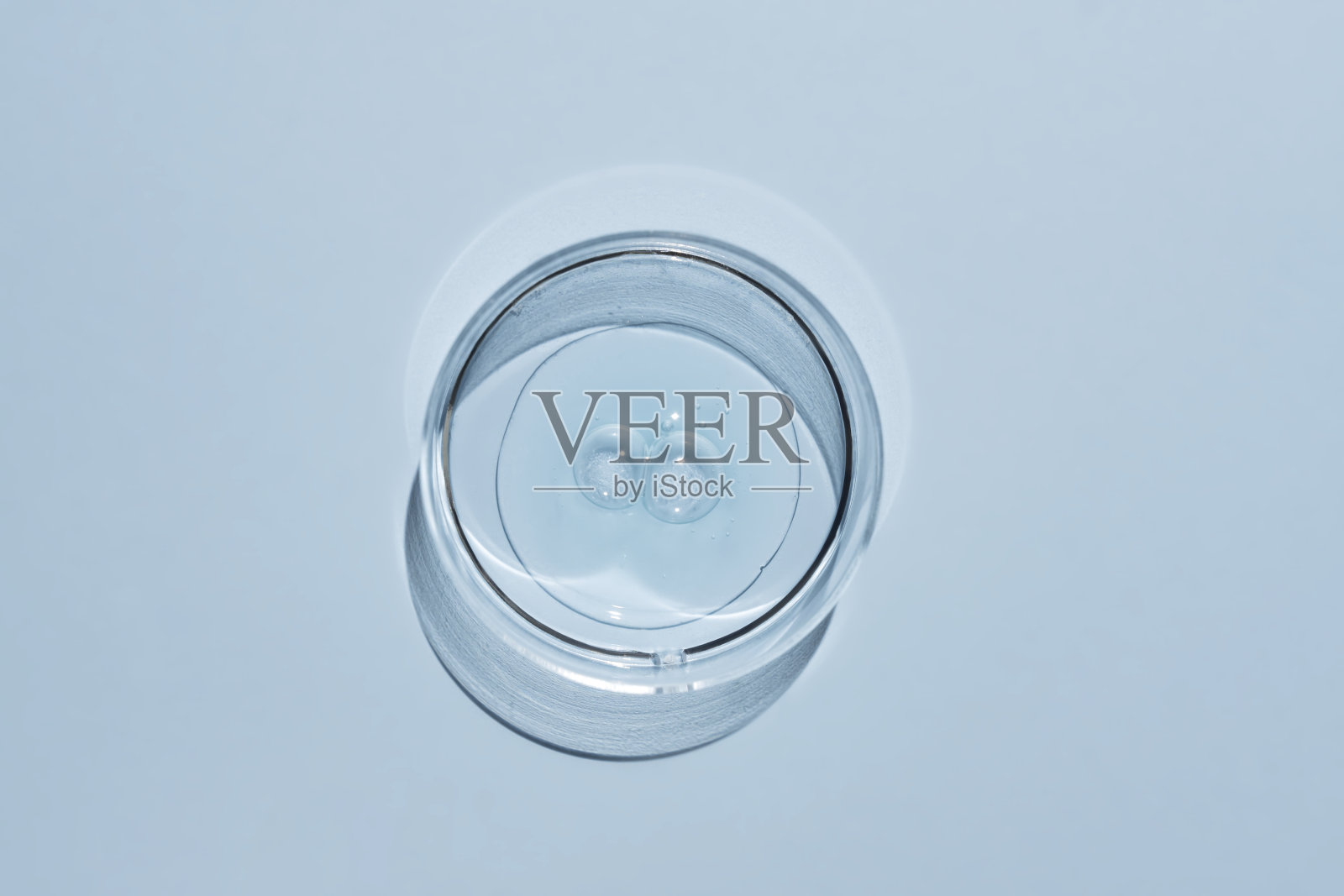 实验室培养皿和面部血清，蓝色背景。替代医学，美容研究。皮肤护理。皮肤病。前视图。照片摄影图片