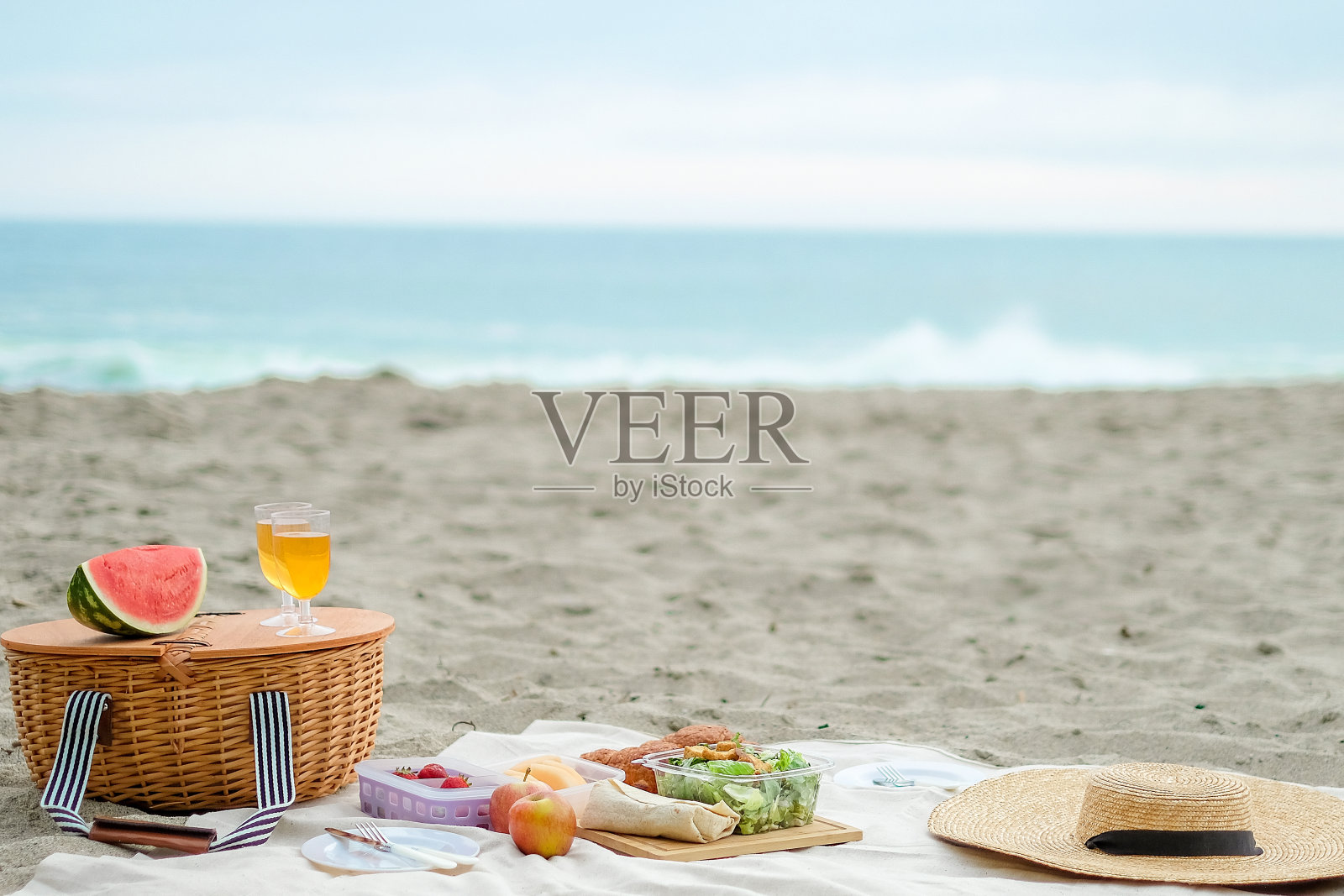 野餐是在海滩上举行的。柳条篮子与食物和饮料的浪漫野餐和放松。冷静和良好的氛围。照片摄影图片