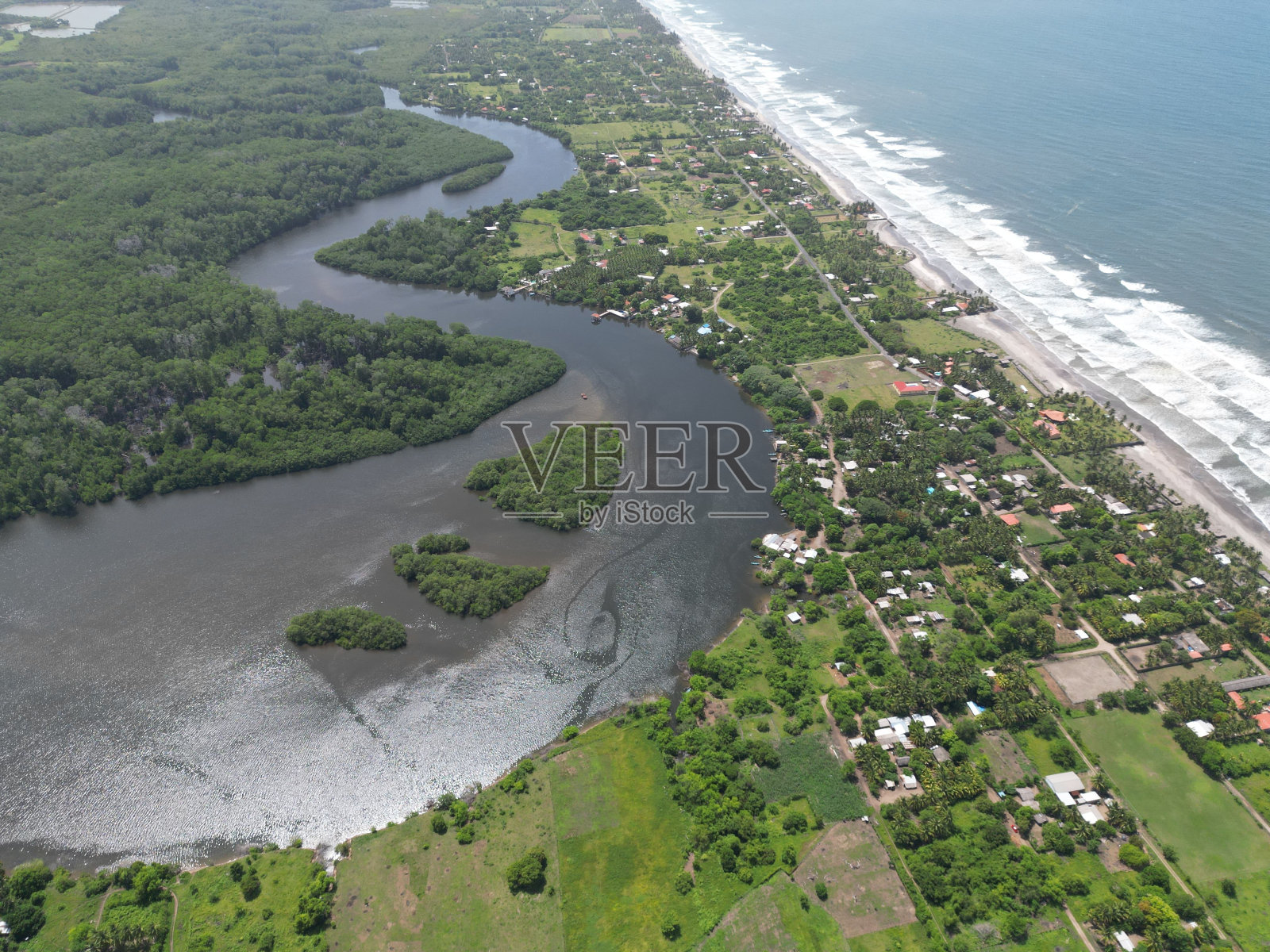 萨尔瓦多埃尔埃斯皮诺海滩的鸟瞰图，郁郁葱葱的绿树和平静的海水照片摄影图片