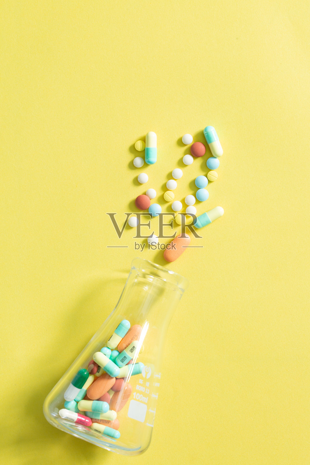 黄色背景上的药丸和药瓶，黄色背景上的玻璃瓶里的彩色药片和药丸胶囊堆着各种各样的药片和药丸。卫生保健特写副本照片摄影图片