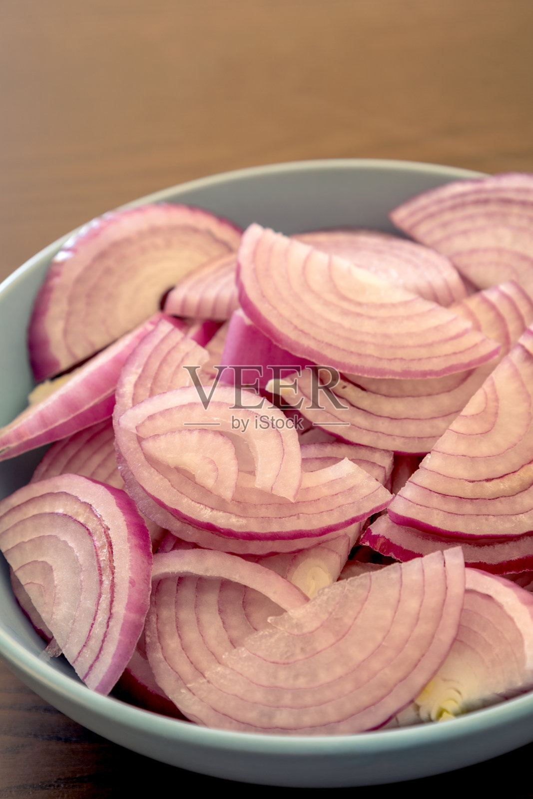 在厨房桌子上的蓝碗里切红洋葱照片摄影图片