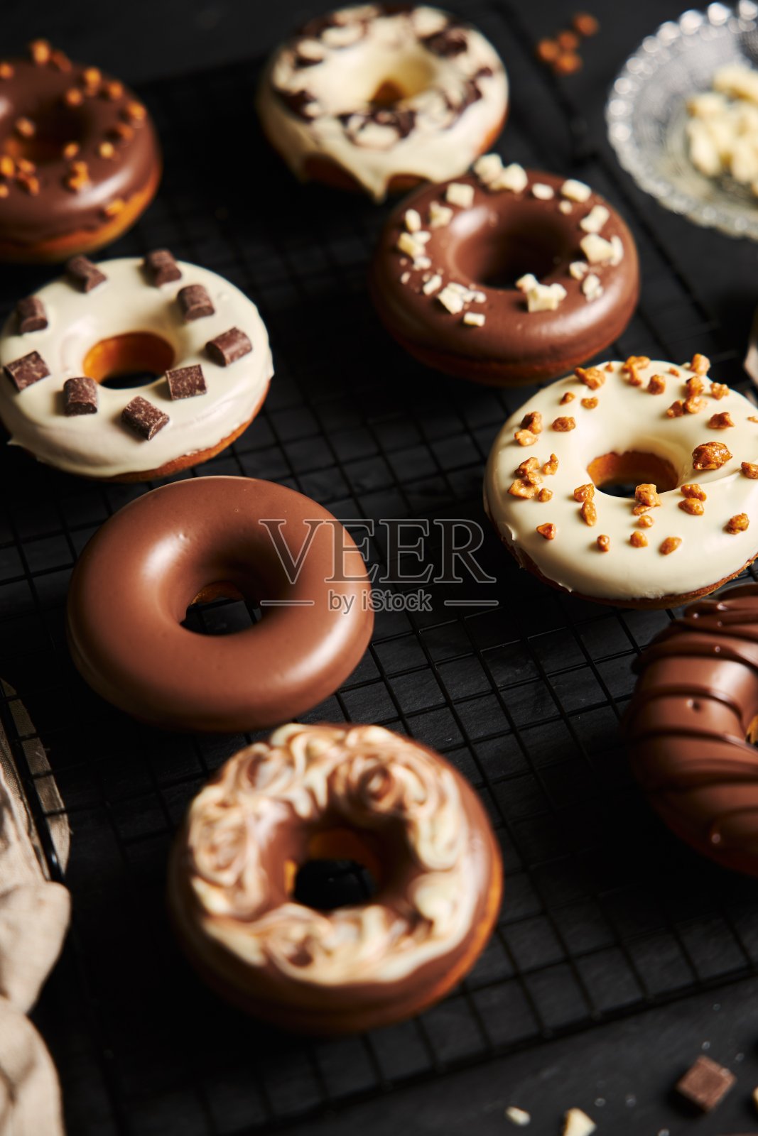 垂直拍摄的美味甜甜圈覆盖着白色和棕色的巧克力釉，放在黑色的桌子上照片摄影图片