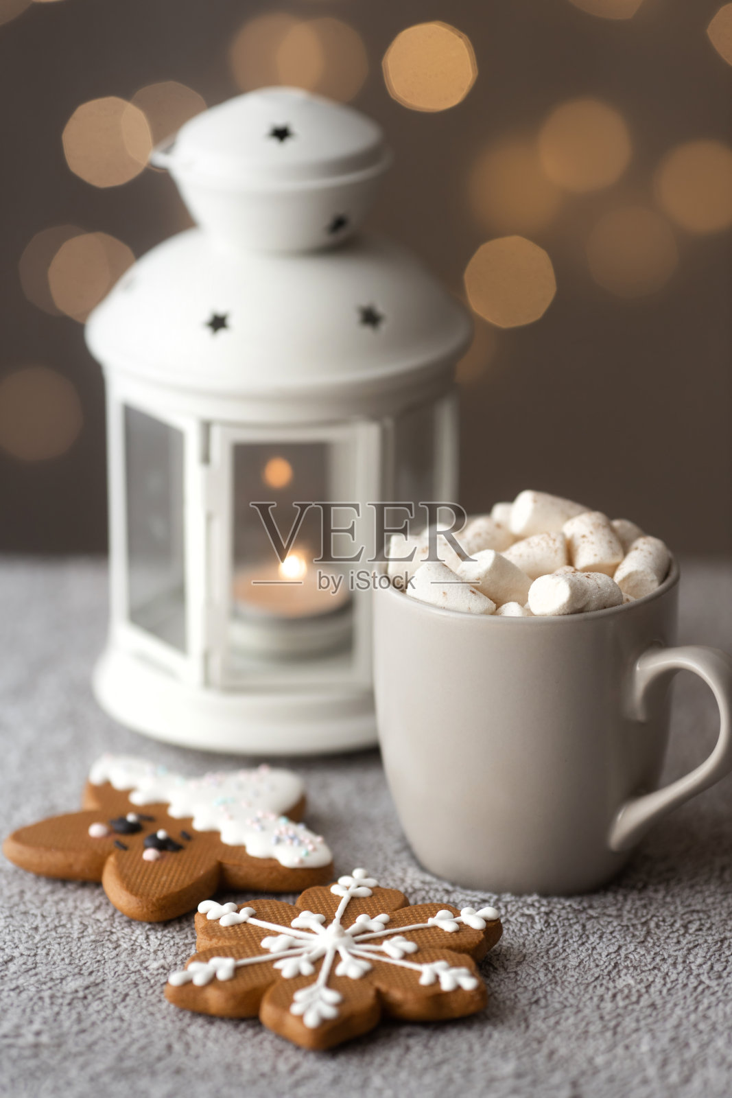 孩子们舒适的冬日早餐，桌上有姜饼饼干，蜡烛灯和灰色的咖啡杯，上面有温暖的散焦灯。圣诞节的气氛照片摄影图片