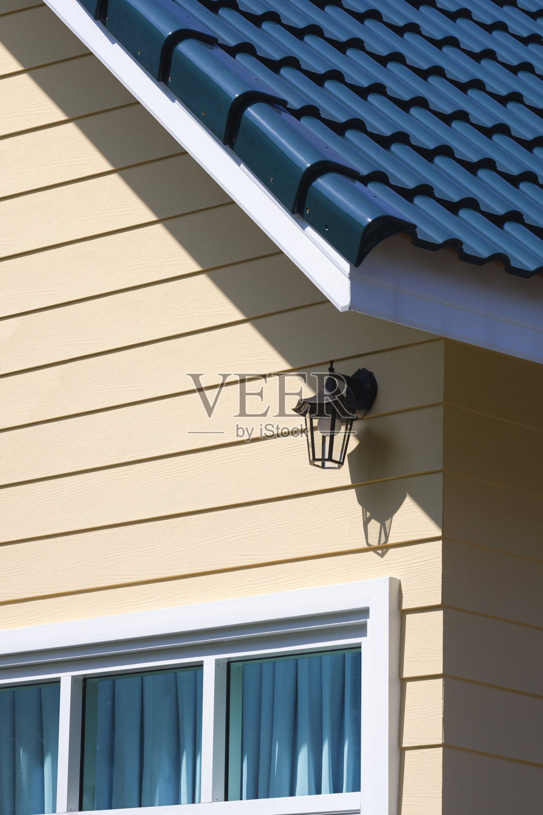 木墙上的玻璃窗和古屋的蓝色瓷砖屋顶的墙灯在透视侧视图和垂直框架照片摄影图片