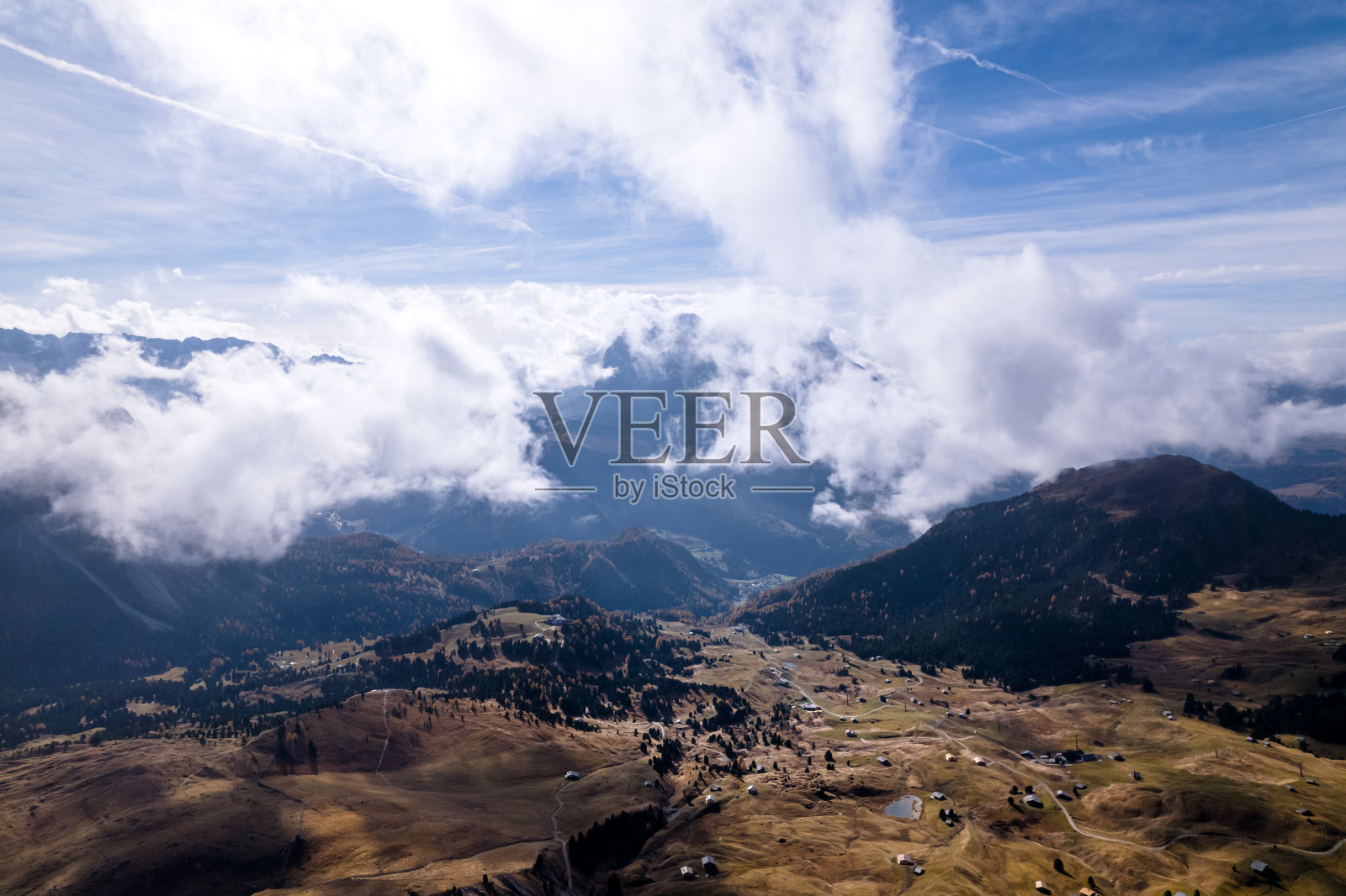 从空中俯瞰秋天色彩缤纷的加尔蒂纳山谷和皮兹波在云层和阳光照耀的天空照片摄影图片