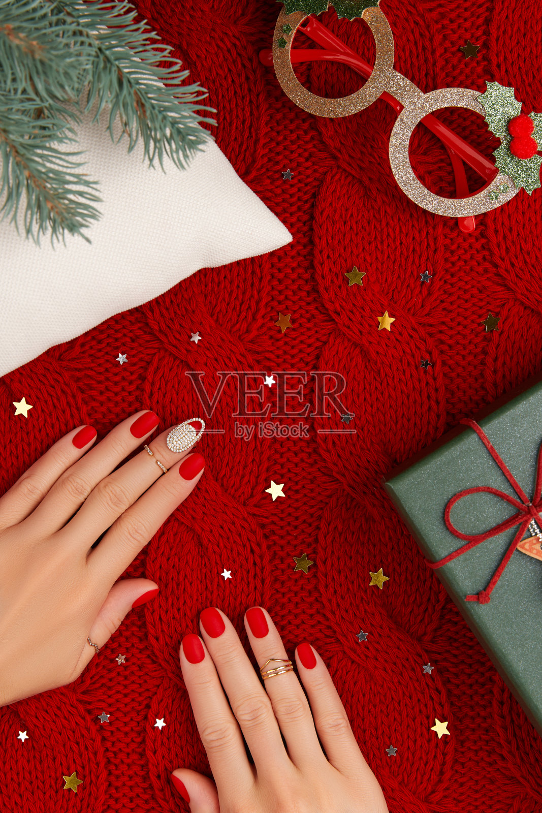 妇女的手与亚光美甲在红色针织被单。圣诞美甲、足疗设计潮流照片摄影图片