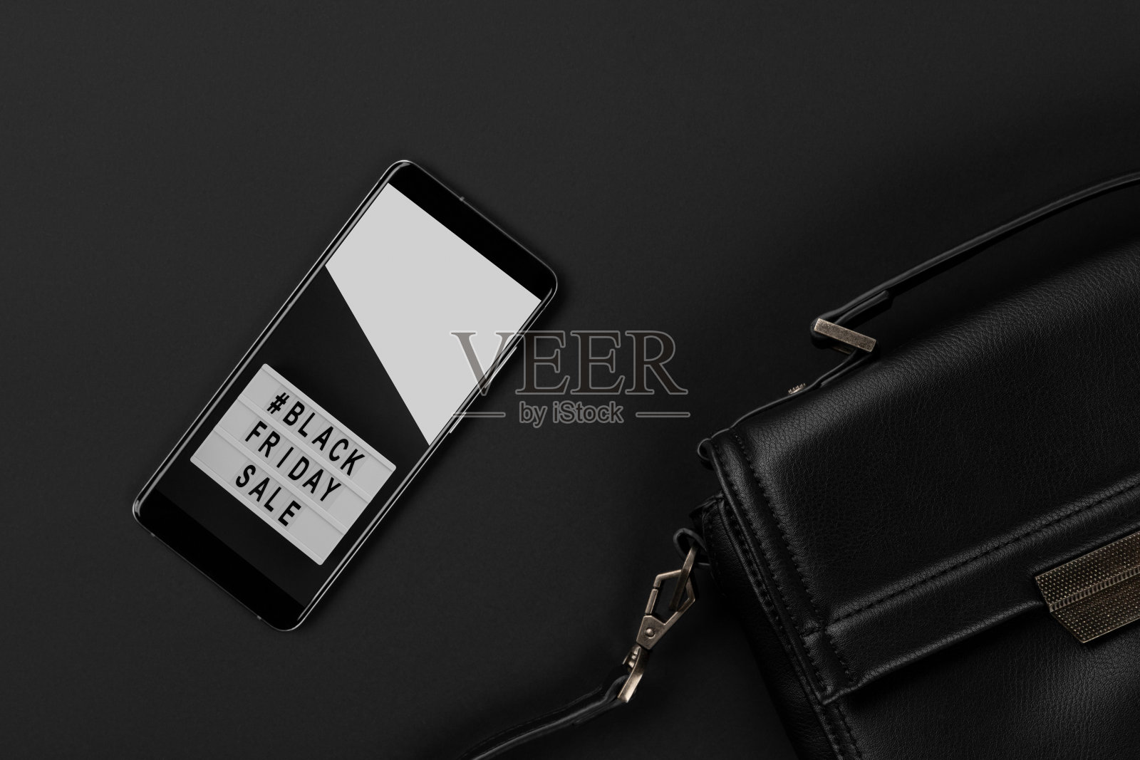 平铺顶部视图包和智能手机在黑色背景。黑色星期五销售照片摄影图片