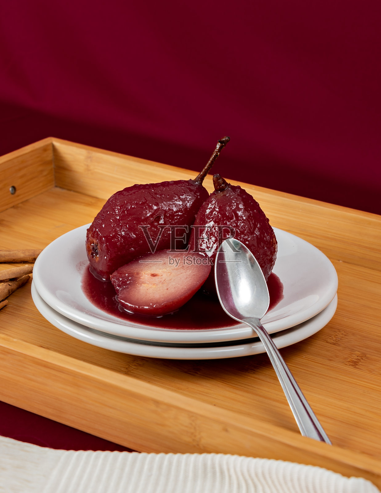 梨加红酒做成的甜点，盛在白色盘子里，放在木托盘里照片摄影图片