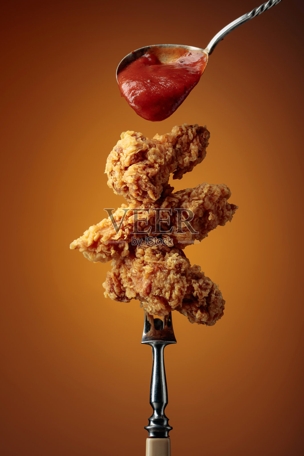 用叉子蘸着番茄酱的炸鸡。照片摄影图片