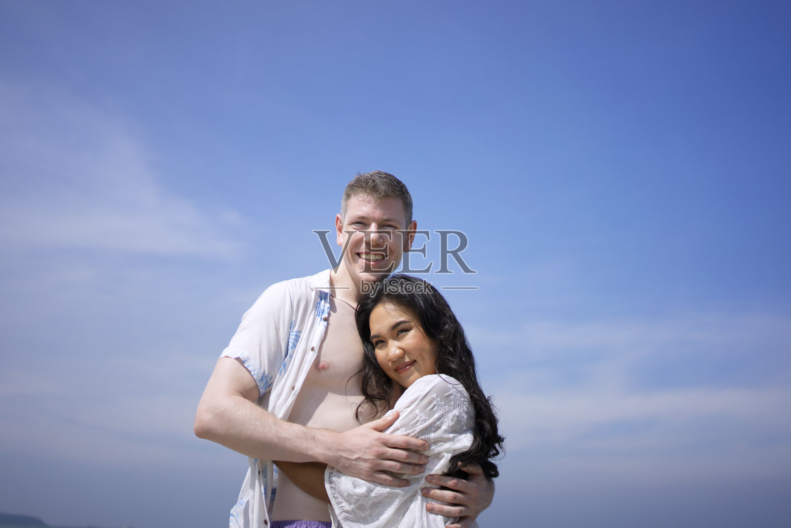 一对年轻夫妇在海滩上散步。照片摄影图片