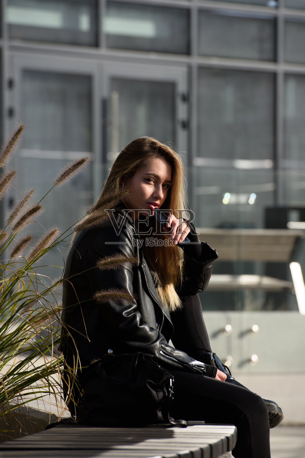 城市妇女坐在公园的长凳上，呼吸着深深的新鲜空气照片摄影图片