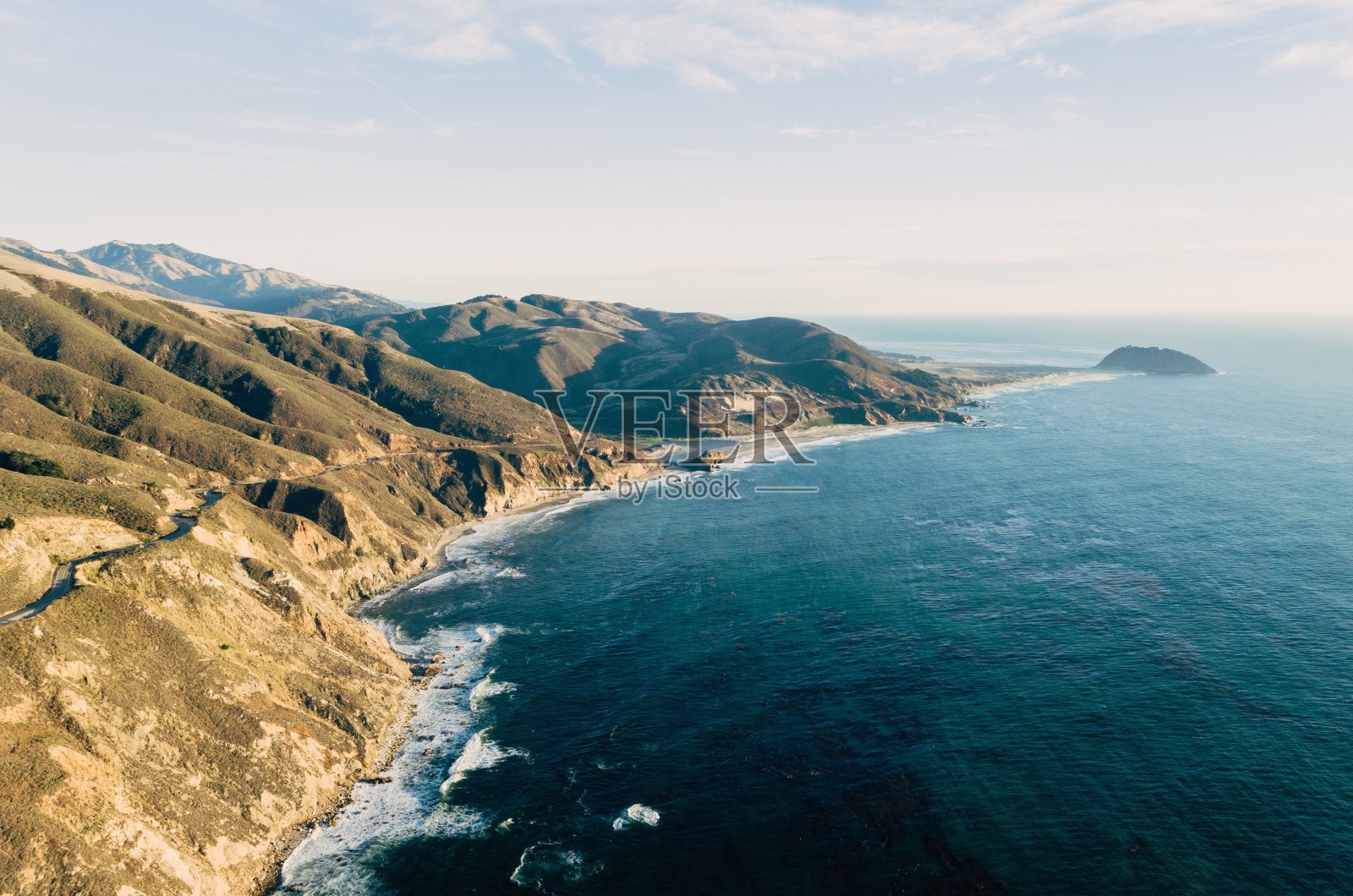 高角度拍摄的海洋在一个覆盖着绿色植物的岩层照片摄影图片