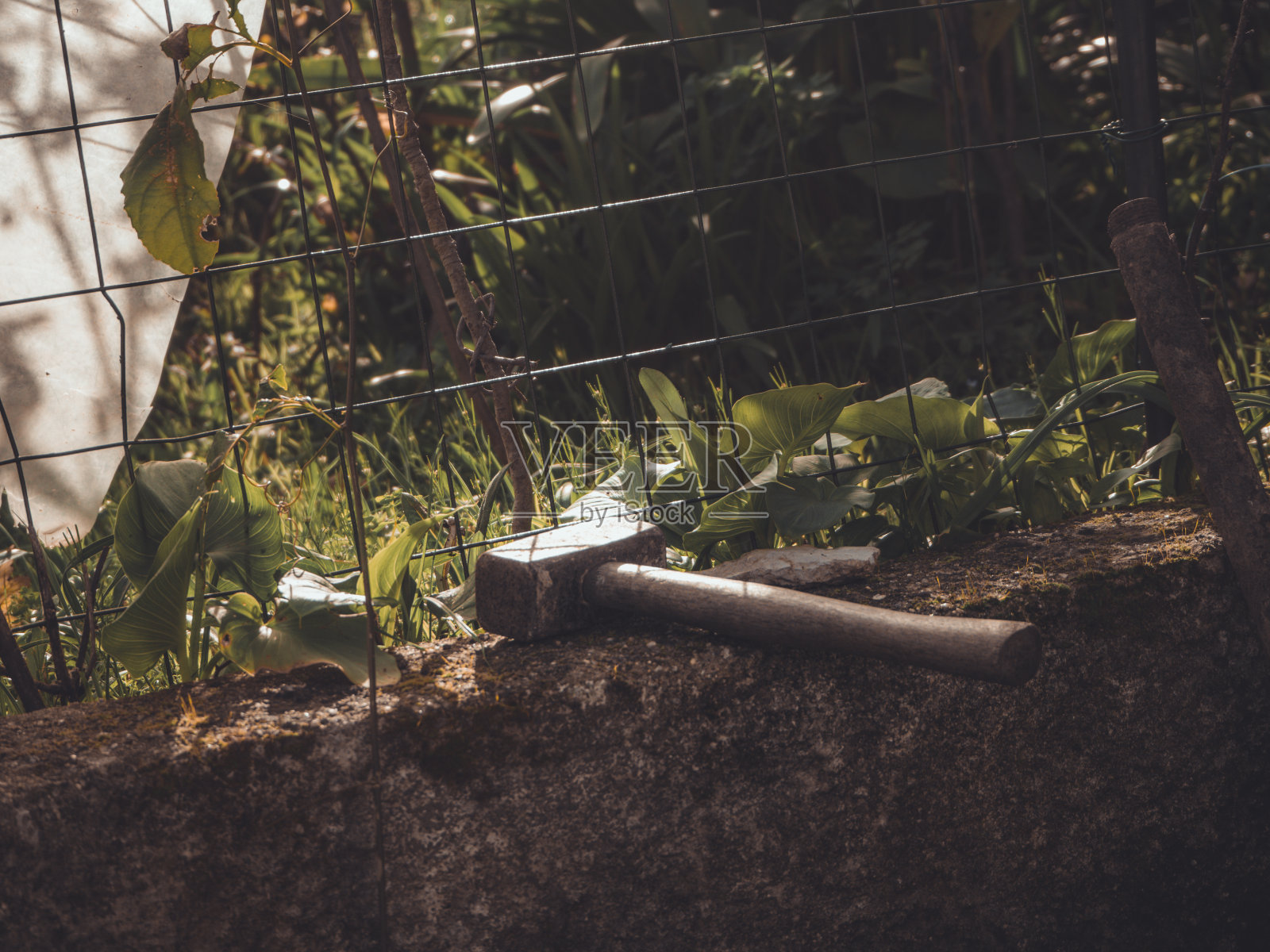 锤子砸在花园金属栅栏附近石头上的漂亮镜头照片摄影图片