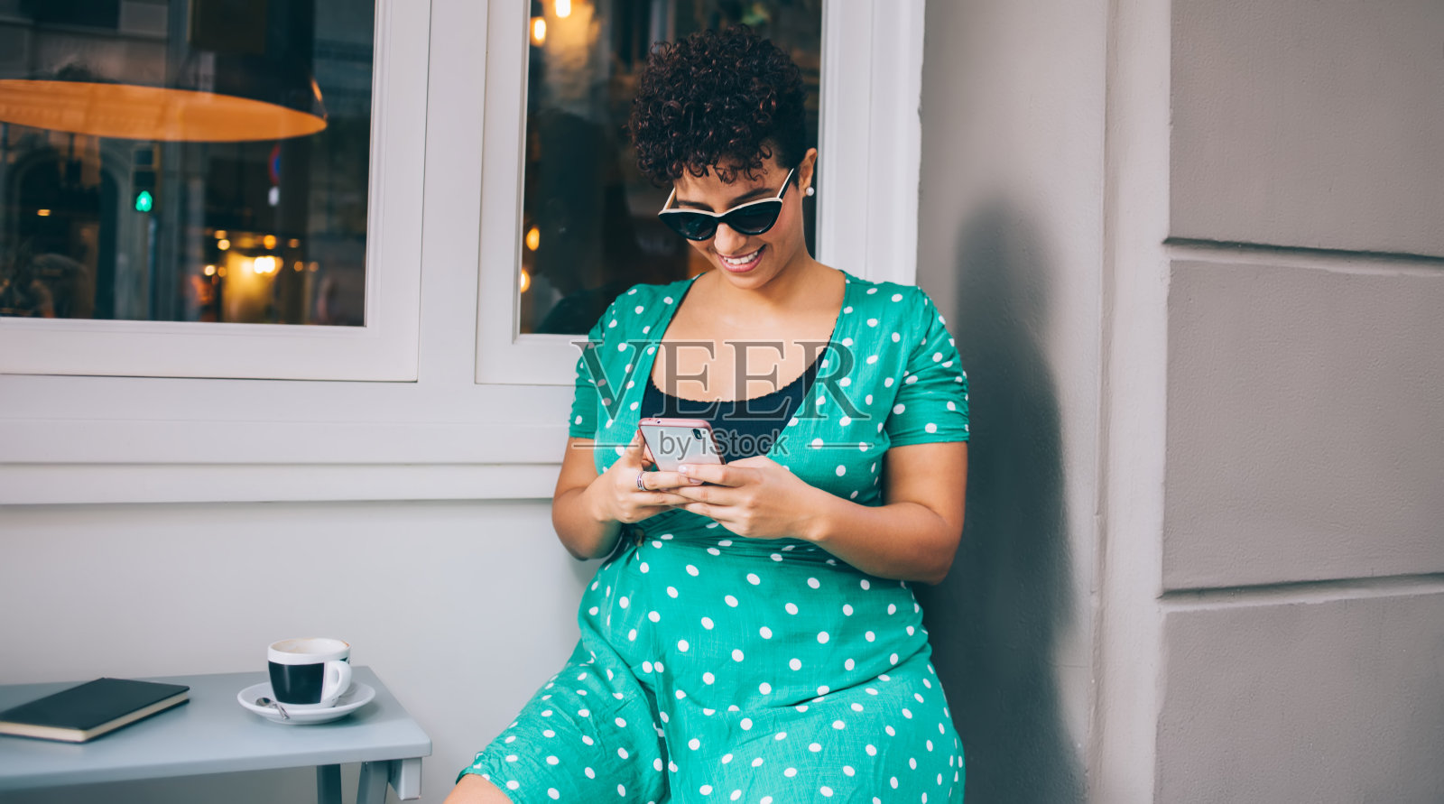 快乐的西班牙妇女搜索下载到手机设备的媒体文件，快乐的千禧一代妇女享受社交网站上连接4g无线的智能手机网络在路边咖啡馆照片摄影图片